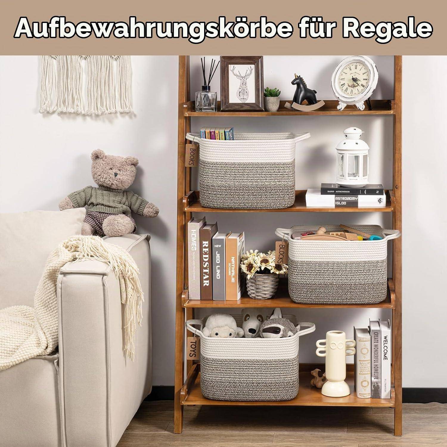 Holzregal mit drei beigen Aufbewahrungskörben, die auf den Regalbrettern organisiert sind, zusammen mit Büchern, Dekorationselementen und einem Teddybär auf einem nahegelegenen Sofa.