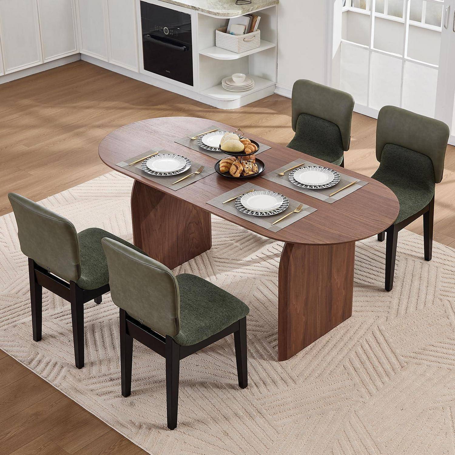 Modernes Esszimmer-Set mit ovalem Holztisch, vier grün gepolsterten Stühlen und Gedeck auf einem hellen Teppich in einem hellen Raum.