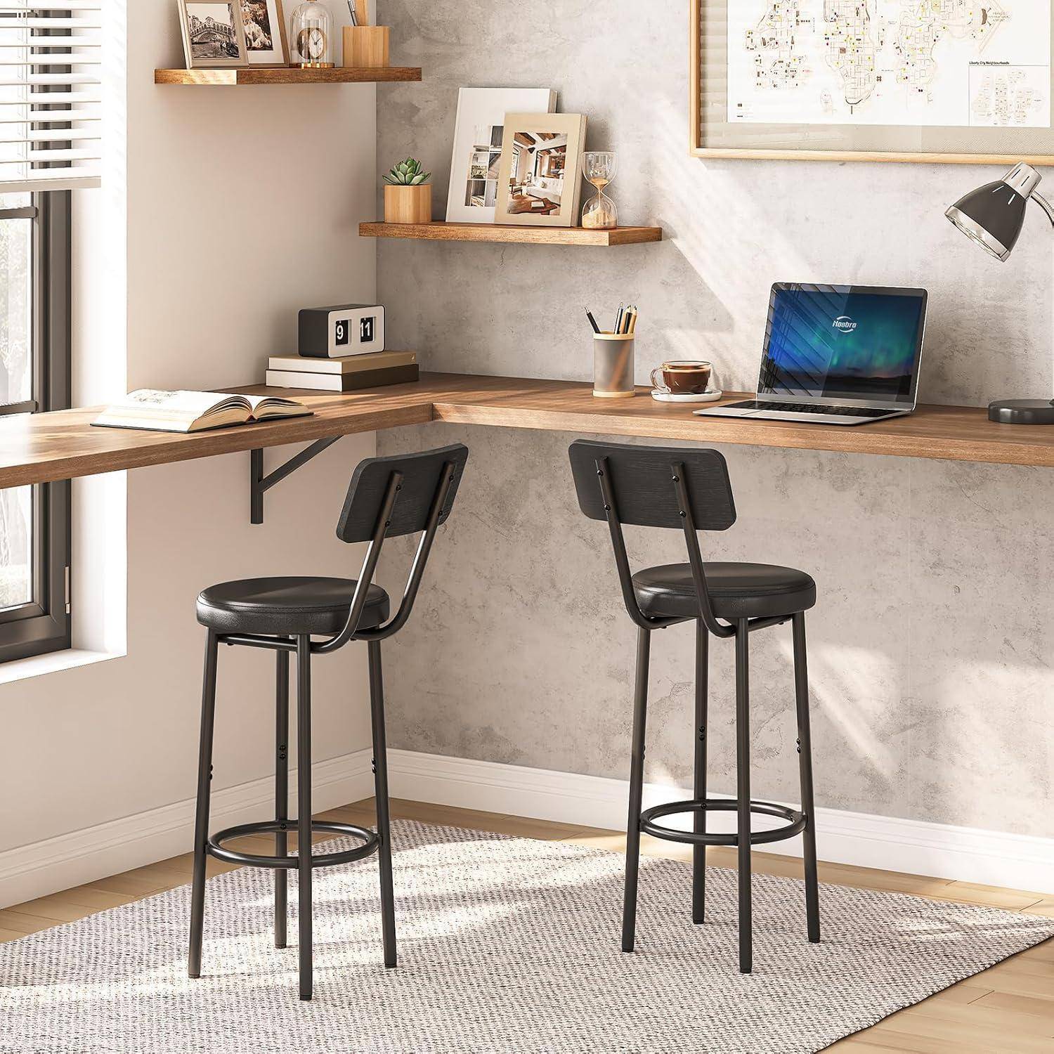 Modernes Home-Office-Eckchen mit zwei schwarzen Barhockern an einem hölzernen Eckschreibtisch, mit einem Laptop, aufgeschlagenem Buch, Regalen und einer Schreibtischlampe.