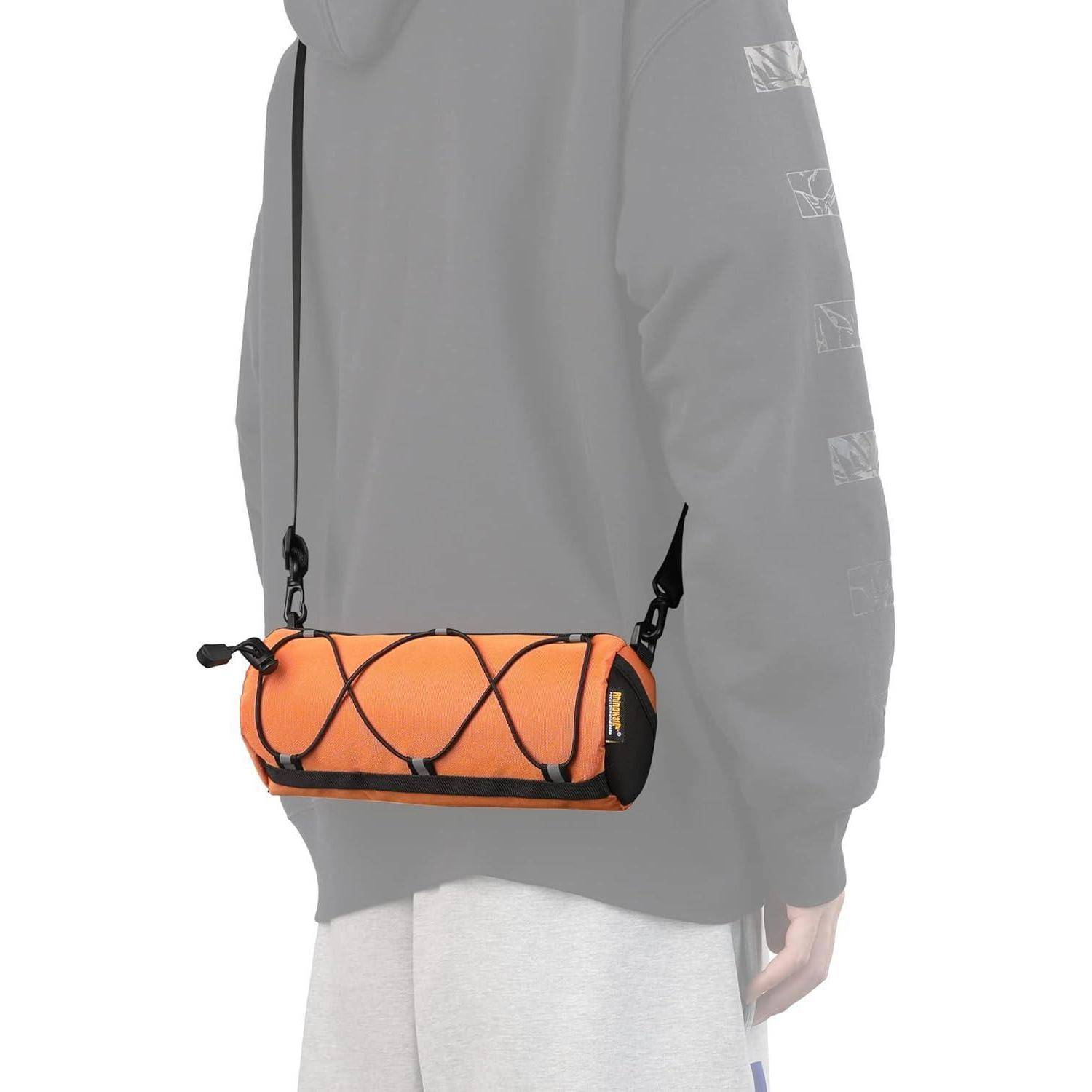 Orange Zylindertasche zum Umhängen mit schwarzem Schnürwerk, über die Schulter getragen und auf Hüfthöhe ruhend.
