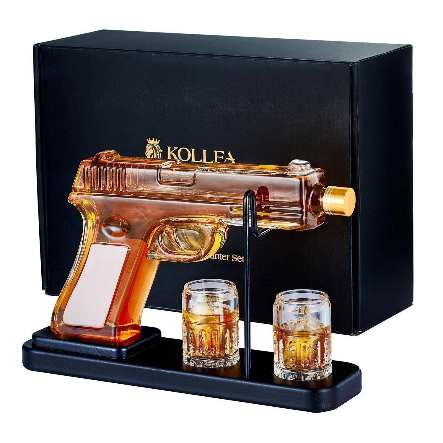 Bernsteinfarbener pistolenförmiger Spirituosenseifter auf schwarzem Ständer mit zwei kleinen Whiskygläsern und schwarzer Präsentationsbox dahinter.
