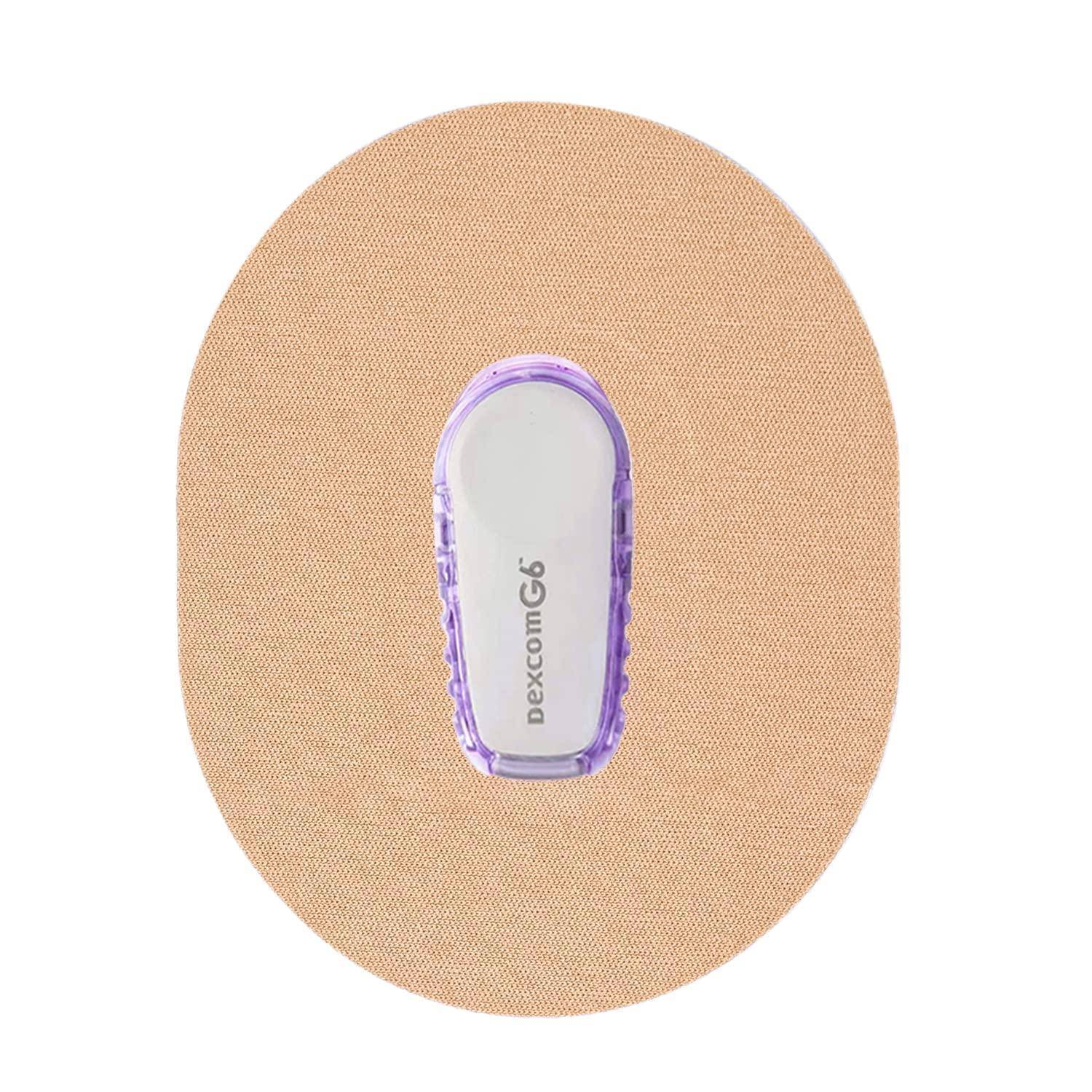 Dexcom G6 Glukose-Sensor mit kontinuierlicher Überwachung auf einem beigen Haftpflaster, Vorderansicht auf weißem Hintergrund.
