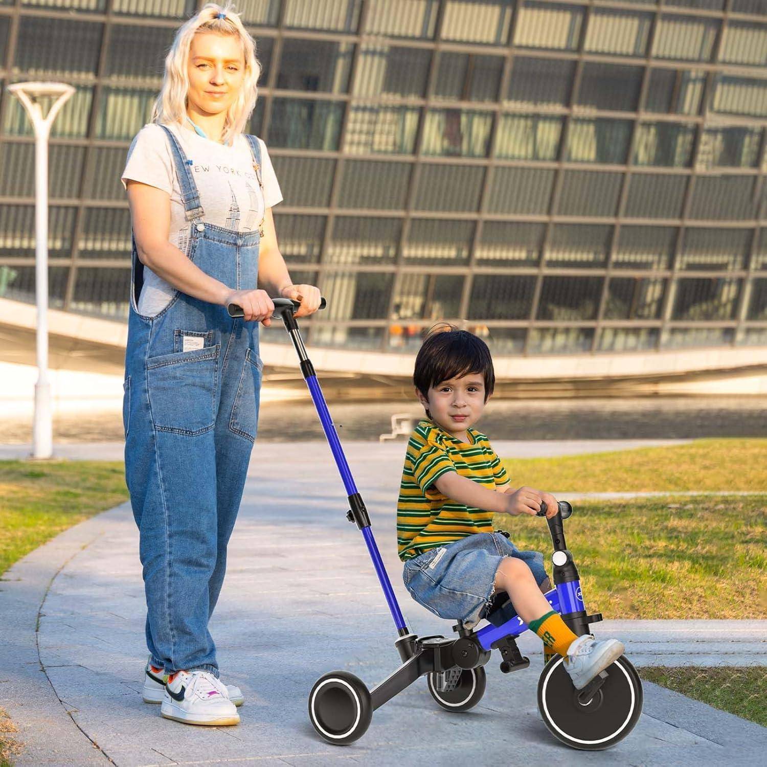 Frau schiebt ein kleines Kind auf einem blauen Dreirad im Freien auf einem sonnigen Gehweg.