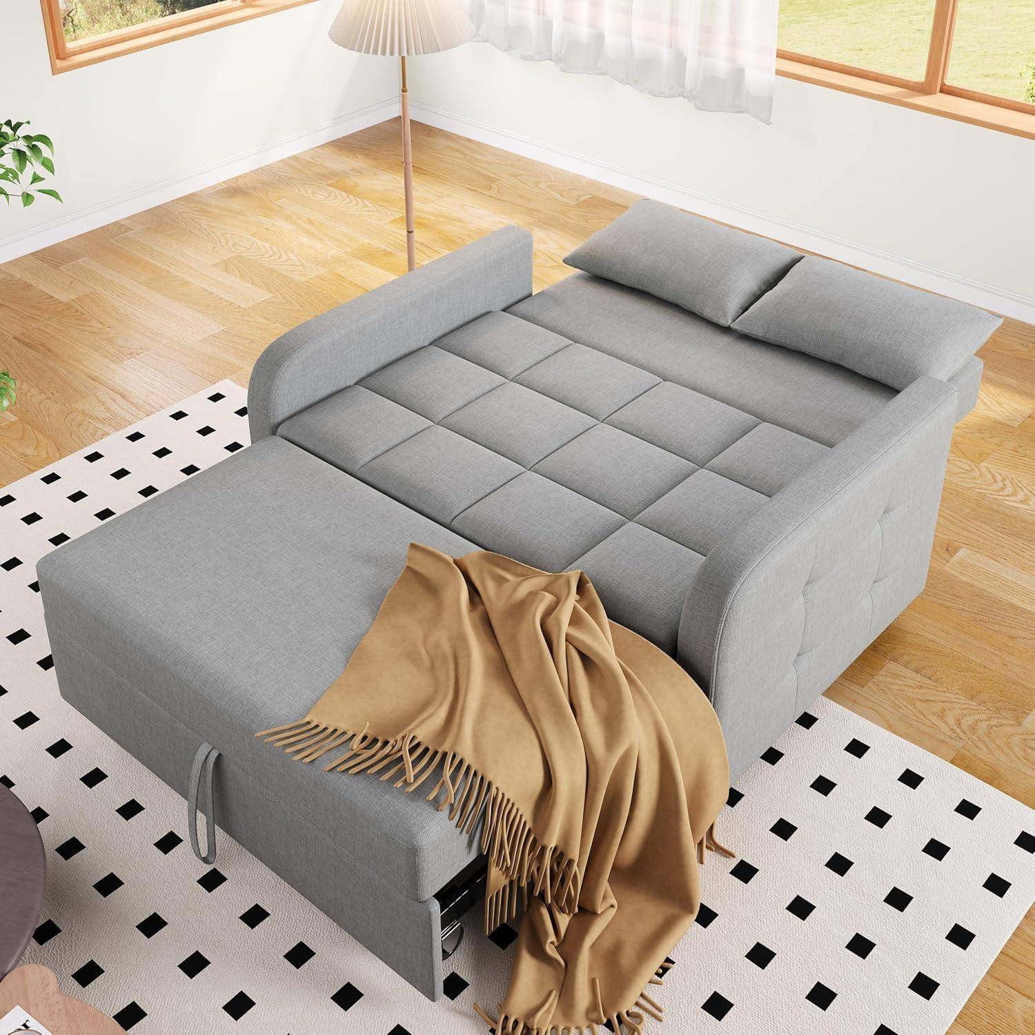 Graues Schlafsofa mit Chaiselongue und zusammengelegter brauner Decke in einem hellen Raum mit gemustertem Teppich und Stehlampe.