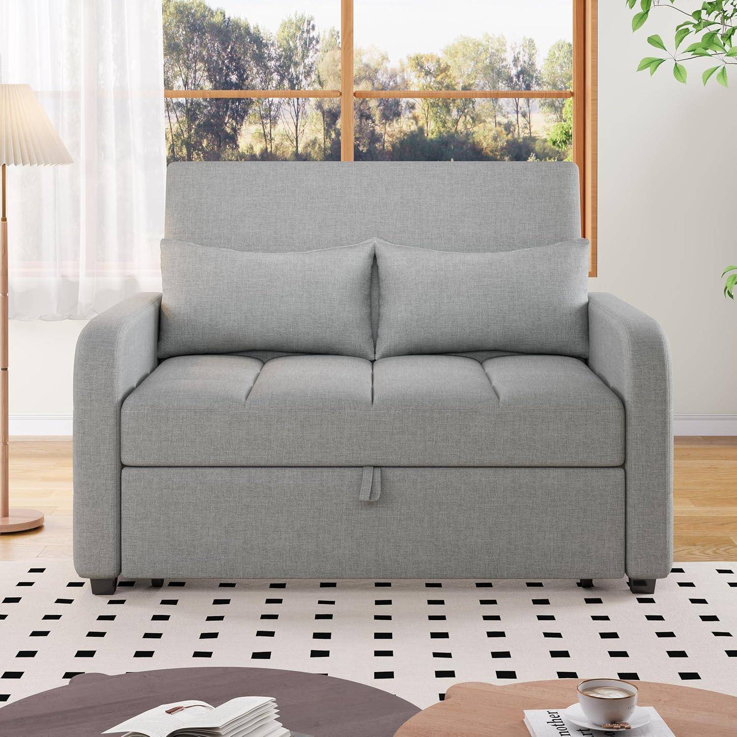 Graues Loveseat-Sofa mit dicken Polstern in einem hellen Wohnzimmer mit einer Stehlampe, Fensterblick und gemustertem Teppich; Couchtisch im Vordergrund.