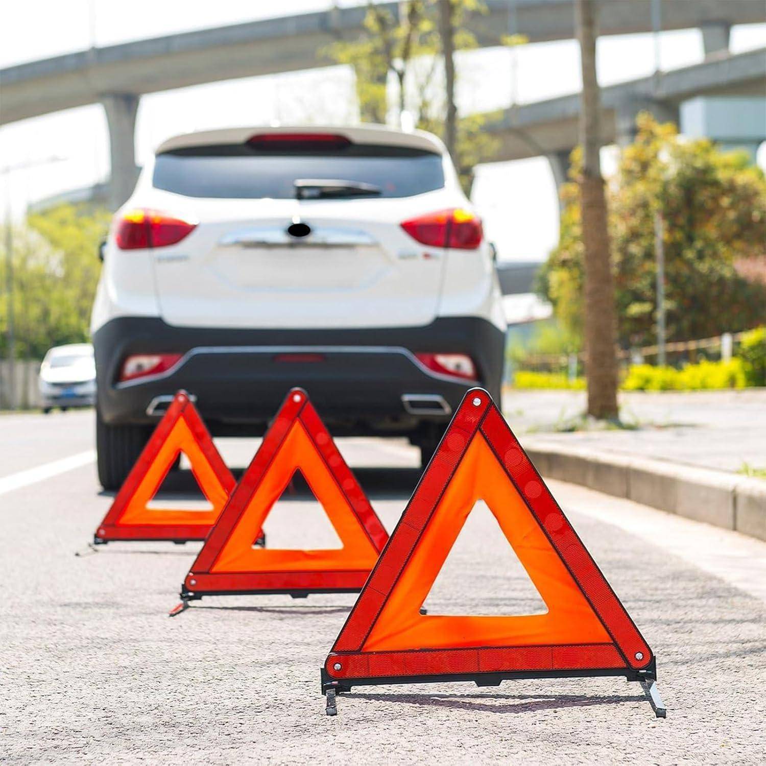 Weißes Geländewagen auf der Straßenseite gestoppt, hinter drei Warndreieken positioniert, was auf eine Panne oder einen Notfall hindeutet.