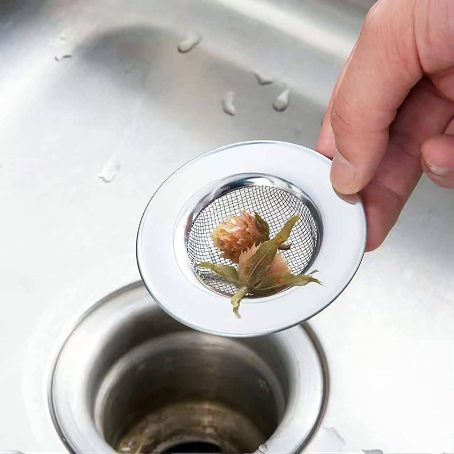 Hand, die einen Spülbeckensieb mit gesammelten Speiseresten über einem Küchenabfluss hält.