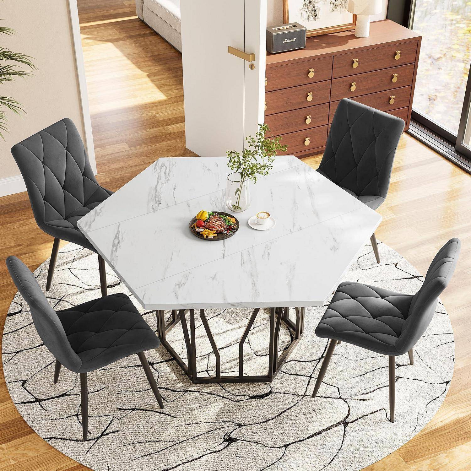 Moderner Essbereich mit einem Tisch im Marmor-Look in Weiß, vier schwarzen gepolsterten Stühlen, einer Vase und einem kleinen Teller auf einem runden Teppich neben einem Sideboard und einem Fenster.