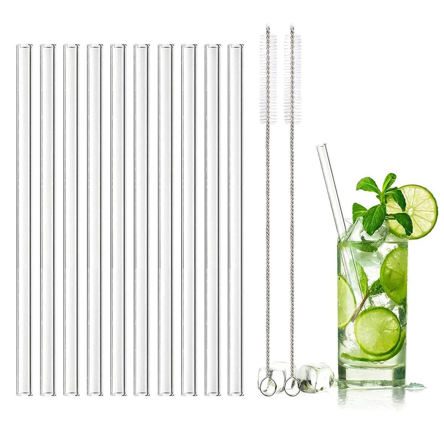 Wiederverwendbare Glastrinkhalme in verschiedenen Größen mit Reinigungsbürsten neben einem Getränk mit Limette und Minze in einem hohen Glas.