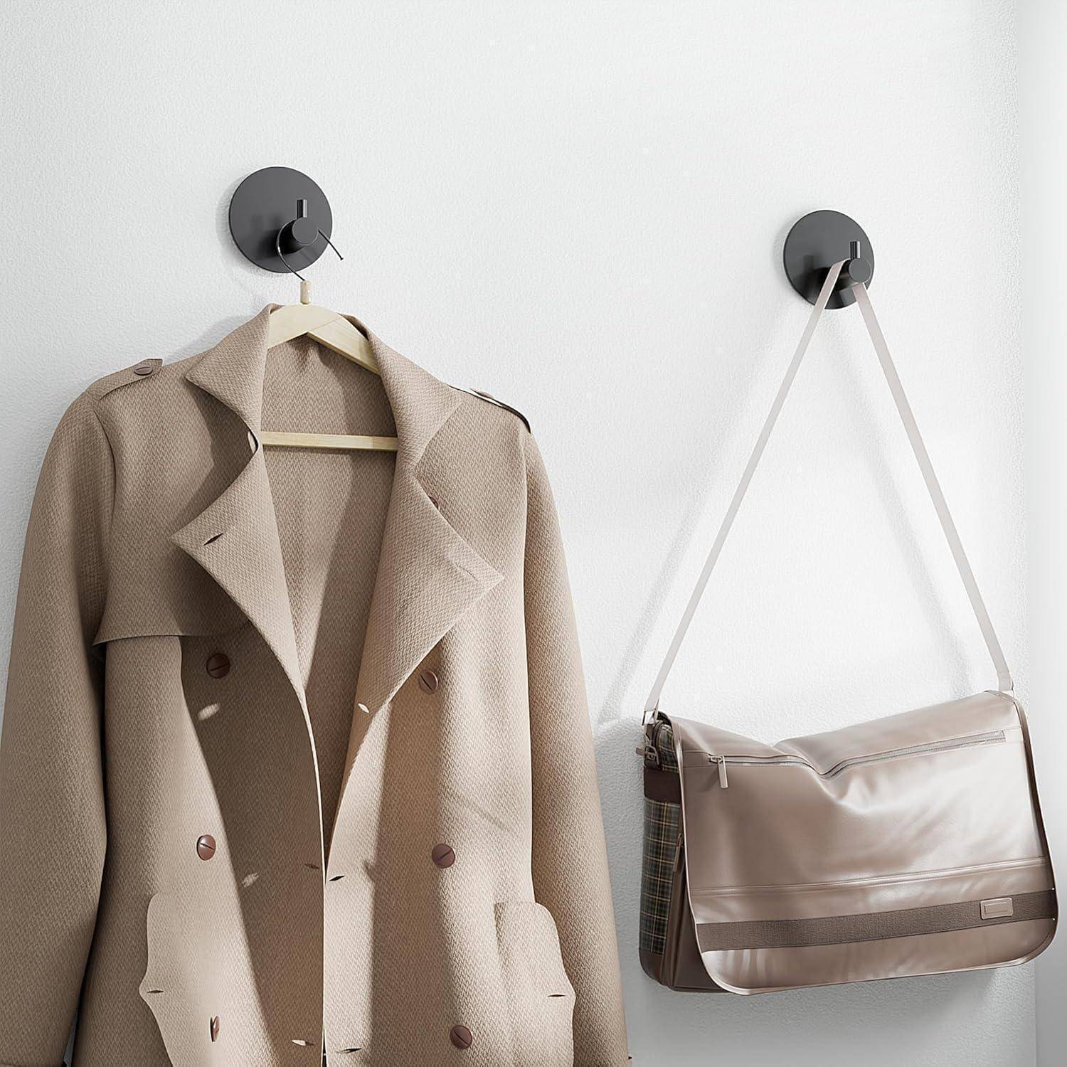 Beiger Trenchcoat und passende Schulttertasche hängen an Wandhaken und zeigen eine minimalistische Modeaufbewahrung.