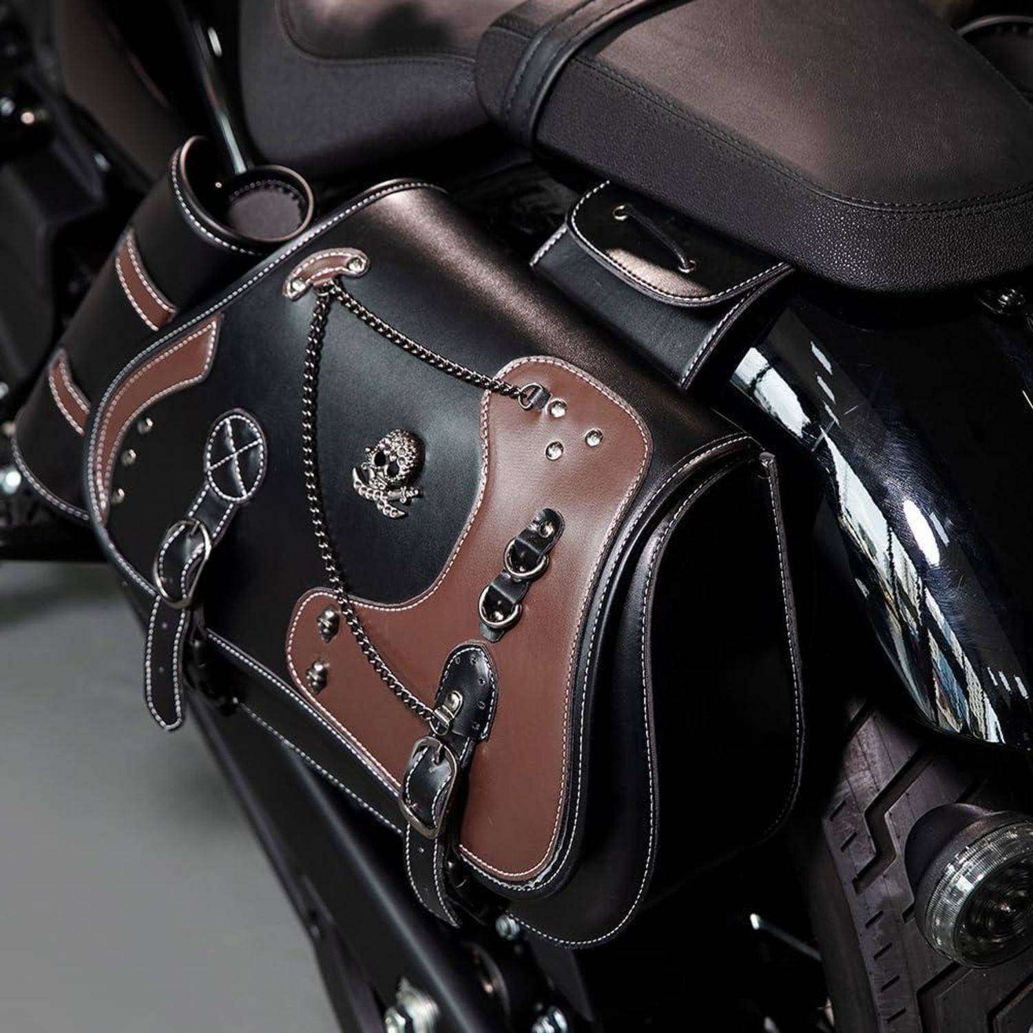 Ledersatteltasche mit Totenkopf-und-Knochen- sowie Friedenszeichen-Aufnähern, befestigt an einem Motorradsitz und Hinterradbereich