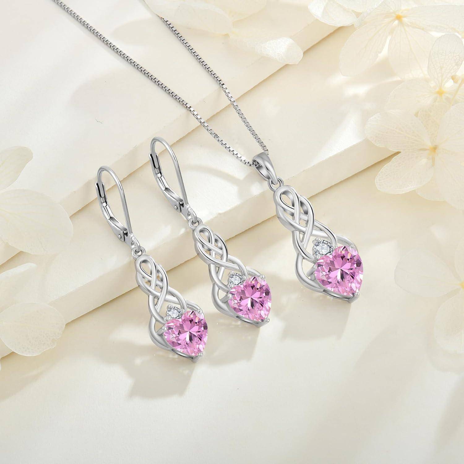 Silberkette und passende Tropfen-Ohrringe mit rosa Edelstein-Herzen auf hellflorigem Hintergrund.