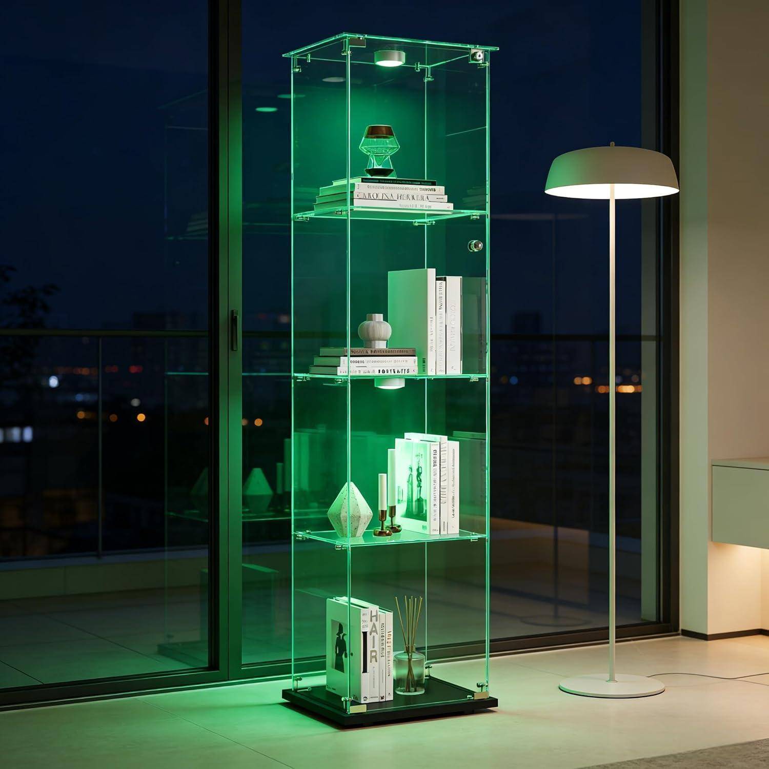 Leuchtender grüner Glasvitrinenschrank mit Bücherregalen und Dekoration neben einer weißen Stehleuchte in einem modernen Zimmer bei Nacht.