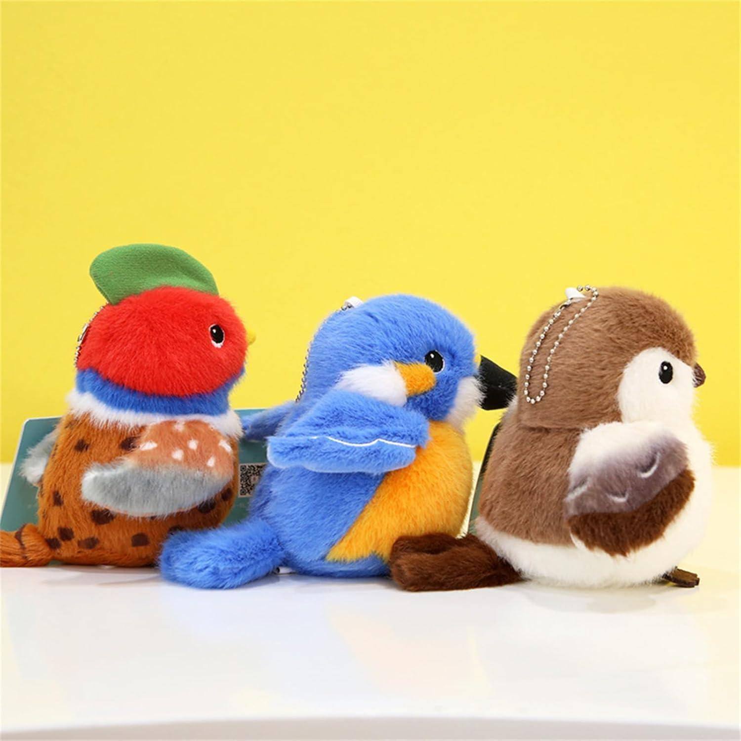 Drei bunte Plüsch-Vogel-Spielzeuge in einer Reihe auf einer weißen Oberfläche vor einem gelben Hintergrund.