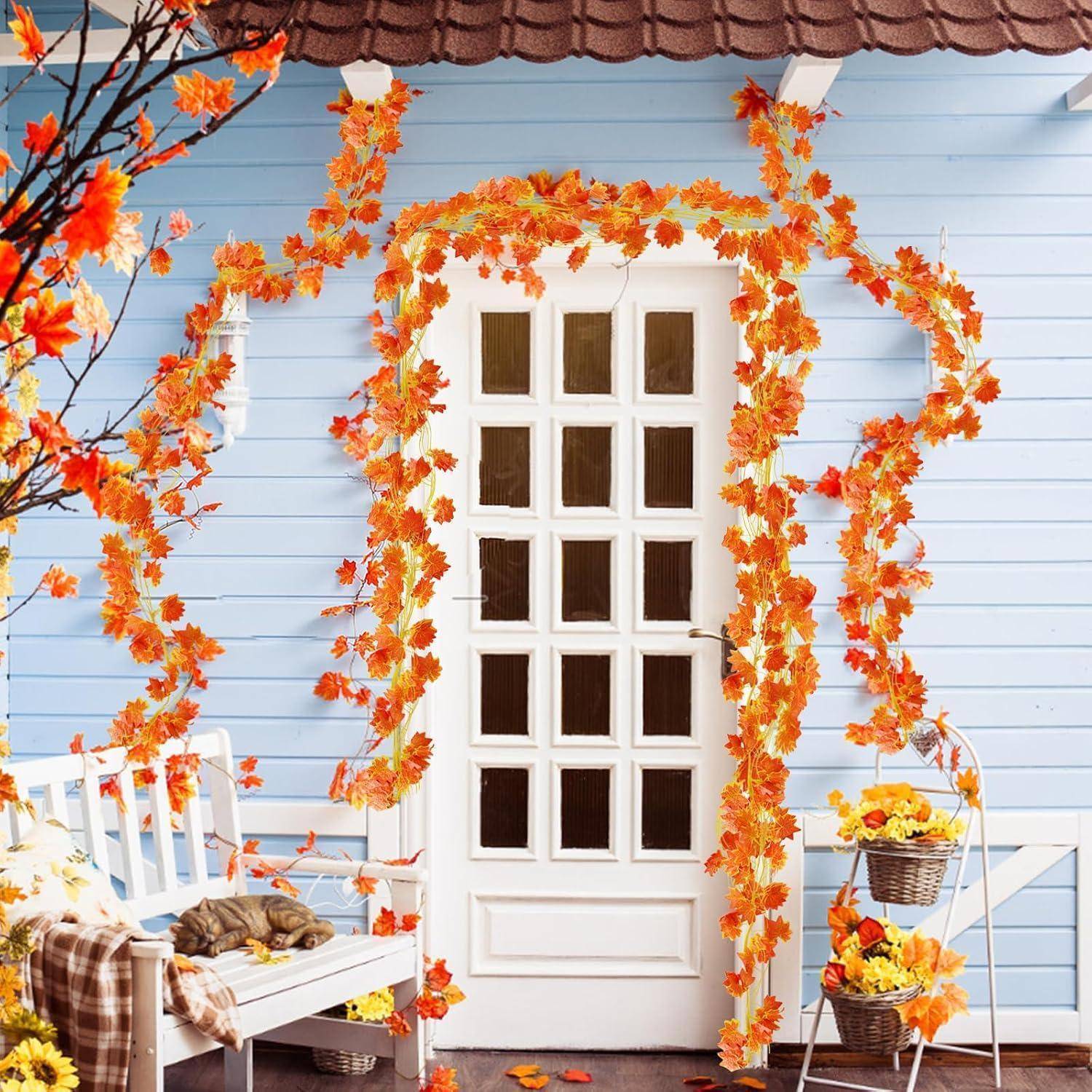Herbstlich dekorierte Veranda mit einer weißen Tür, umrahmt von orangefarbenen Blättern, einer Bank mit einem schlafenden Hund und Körben mit Herbstblumen.