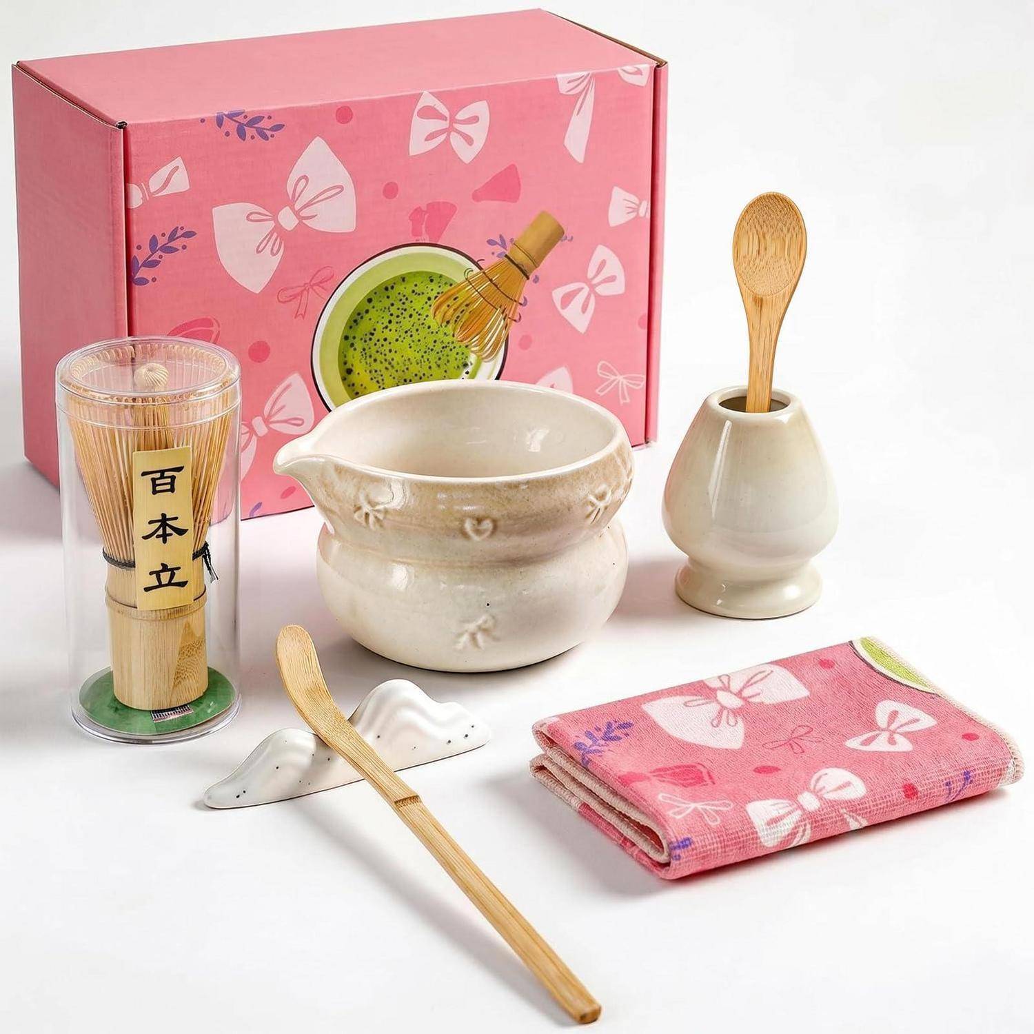 Rosa Geschenkset mit einer Keramikschale, Bamboo-Besen und Löffel, Holzlöffelhalter, Bambus-Matcha-Tasse und gefaltetem rosa Tuch mit Schmetterlingsmuster.