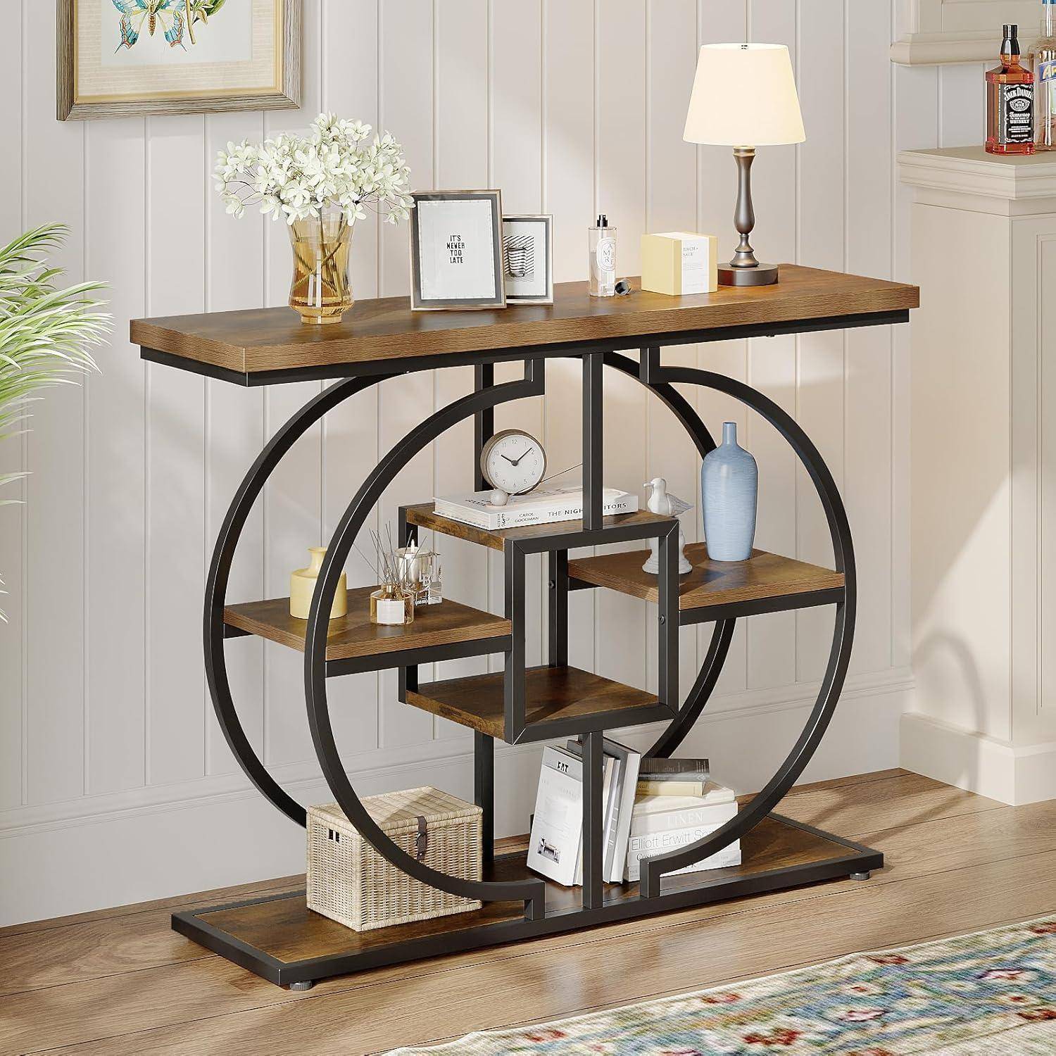 Moderner Konsolentisch mit kreisförmigem schwarzem Metallrahmen und Holzregalen, dekoriert mit Lampe, Vase, Büchern, Blumen, Uhr und Körben in einer Wohnraumeinrichtung.
