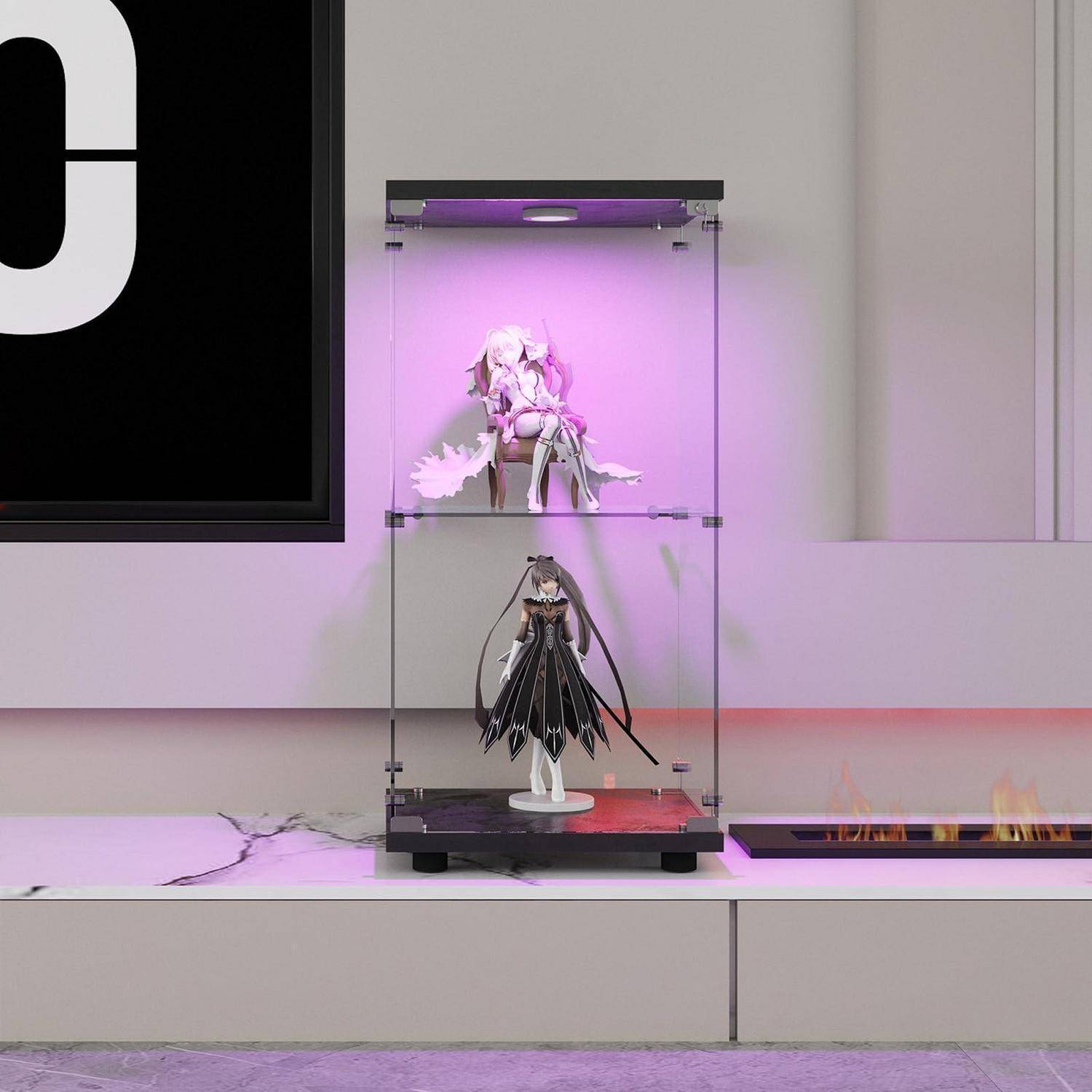 Zwei Anime-Figuren, die in einer transparenten Glasvitrine auf einem Regal ausgestellt sind, beleuchtet durch violettes Licht; ein an der Wand montierter elektrischer Kamin leuchtet daneben.