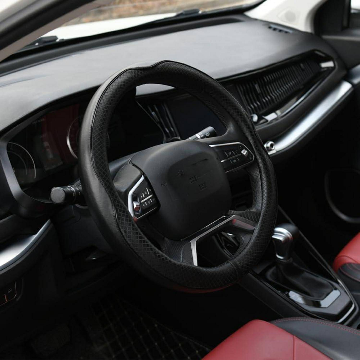 Inneres eines modernen Autos, das das Lenkrad, das Armaturenbrett, die mittlere Konsole und rote Sitze zeigt.