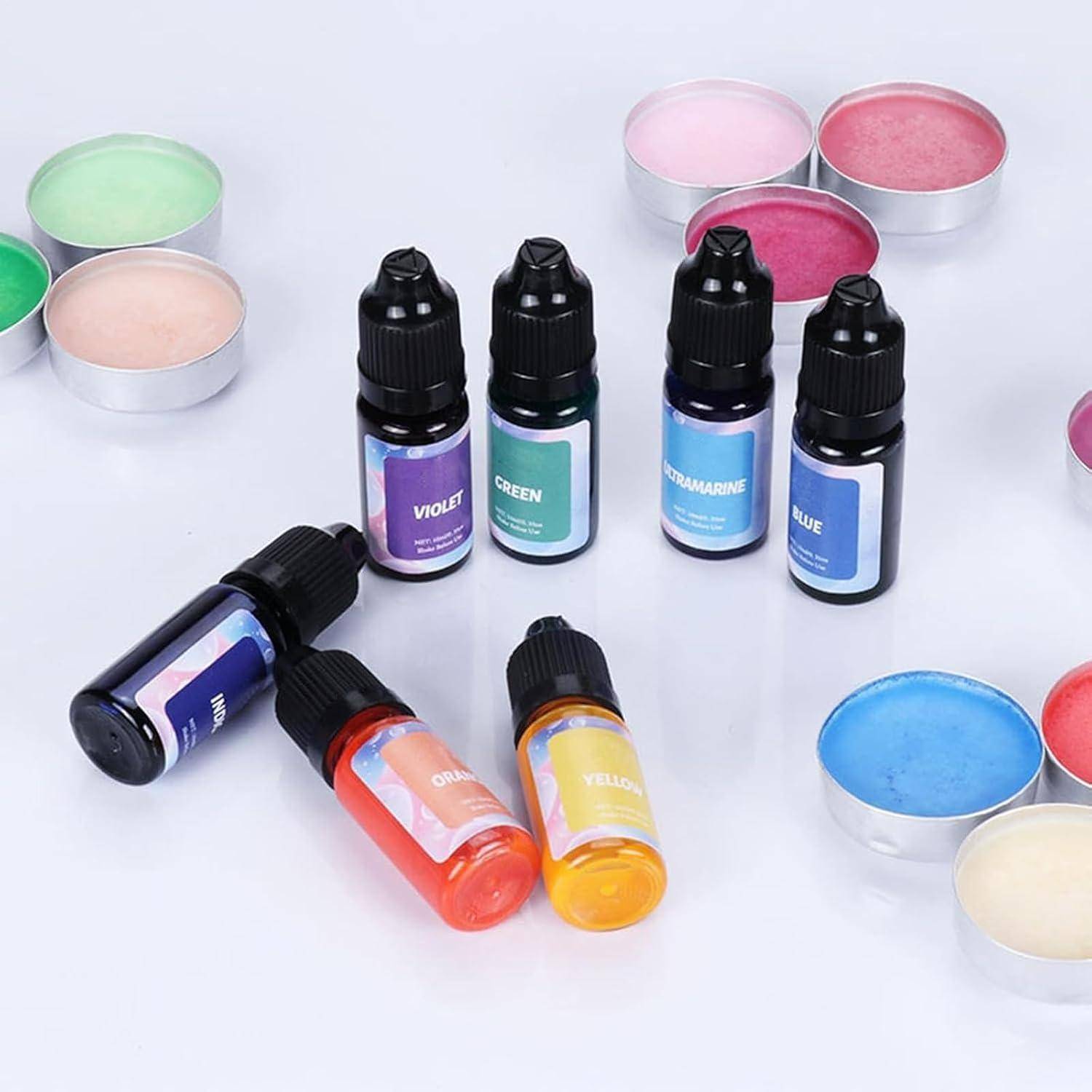 Assortierte flüssige Farbtusche in kleinen Tropfflaschen, beschriftet mit Violett, Grün, Ultramarinblau, Blau, Orange und Gelb, angeordnet mit passenden Farbpfannen.