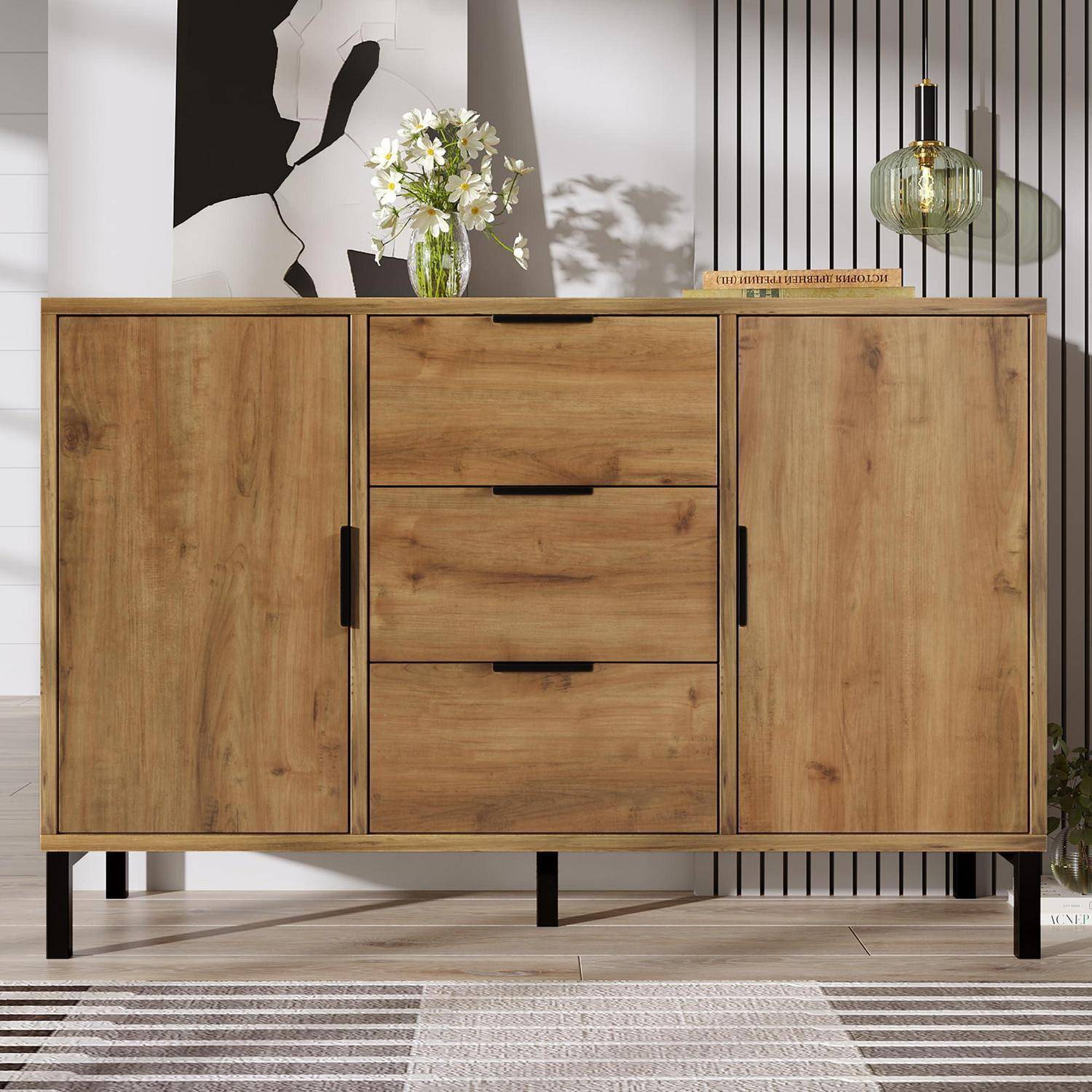 Holzschrankwagen mit zwei Türen und drei mittleren Schubladen in einem modernen Zimmer, belegt mit einer Blumenvase und einer Lampe.