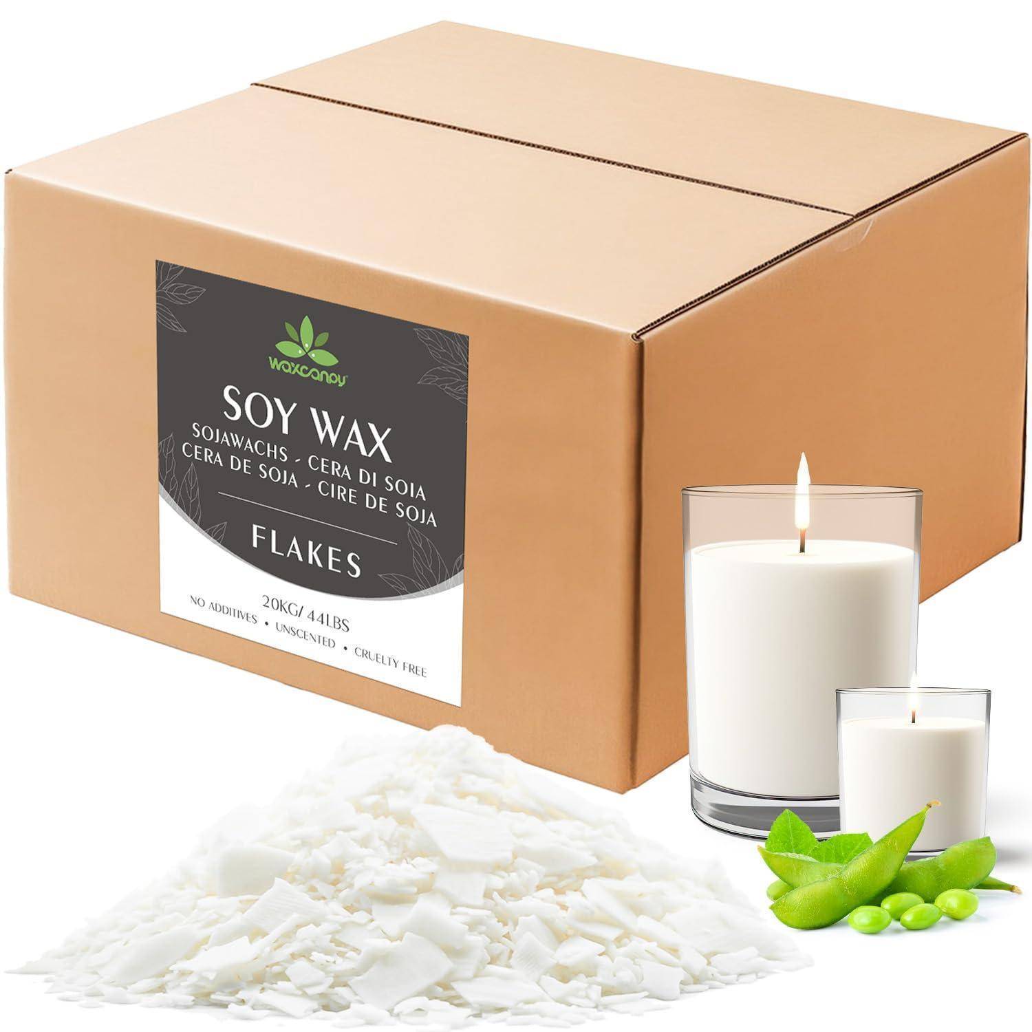 Behälter mit Sojawachsflocken, einer brennenden Kerze und grünen Blättern, was auf die Verpackung von Kerzenwachs hindeutet.