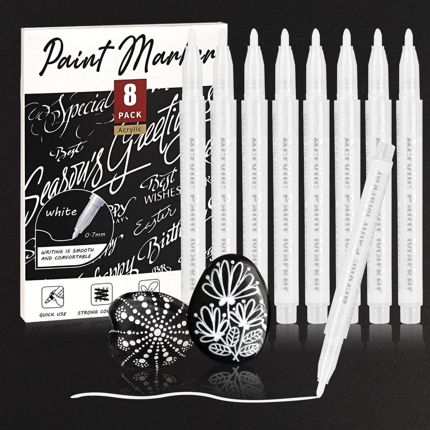 Packung weißer Acrylmarker mit dekorativen Spitzendesigns, gezeigt mit Einzelhandelsverpackung, ein Marker schreibt eine weiße Linie, und zwei dekorierte Steine.