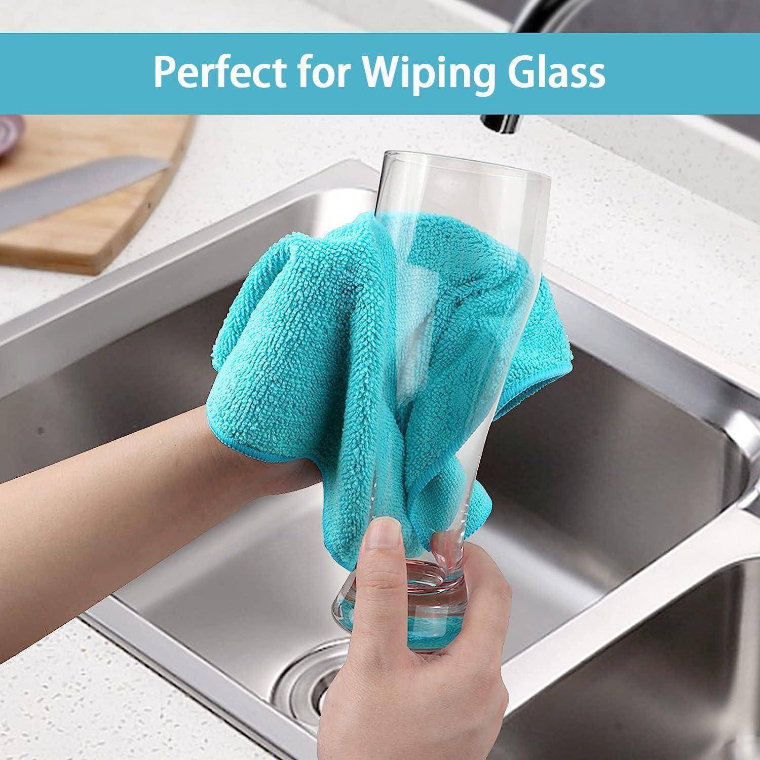 Hand wischt ein Trinkglas mit einem türkisfarbenen Mikrofasertuch über einem Küchenspülbecken ab; Text liest sich „Perfekt zum Abwischen von Glas