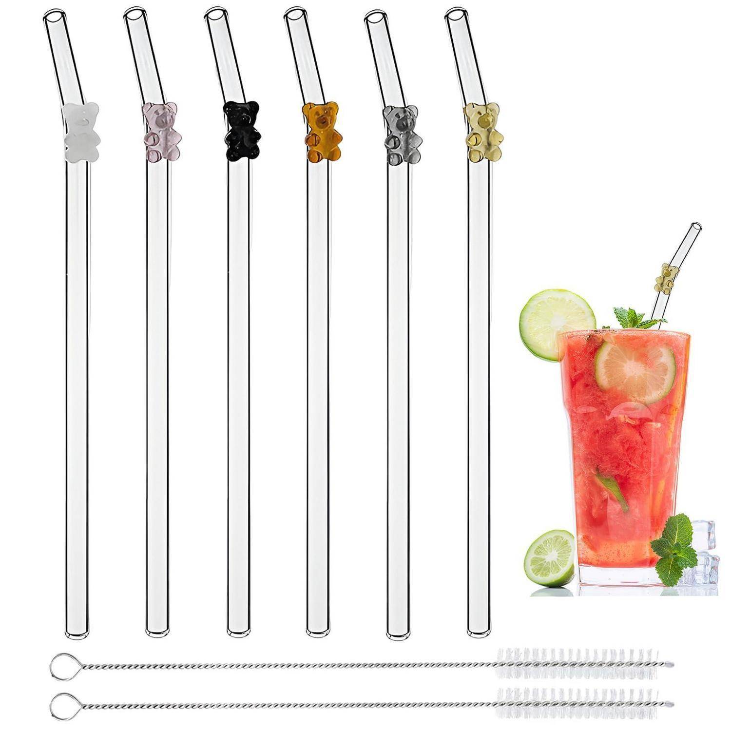 Satz aus sechs durchsichtigen Glastrinkhalmen mit farbigen Teddybär-Akzenten und zwei Reinigungsbürsten, dargestellt neben einem roten Cocktail, garniert mit Limette und Minze.