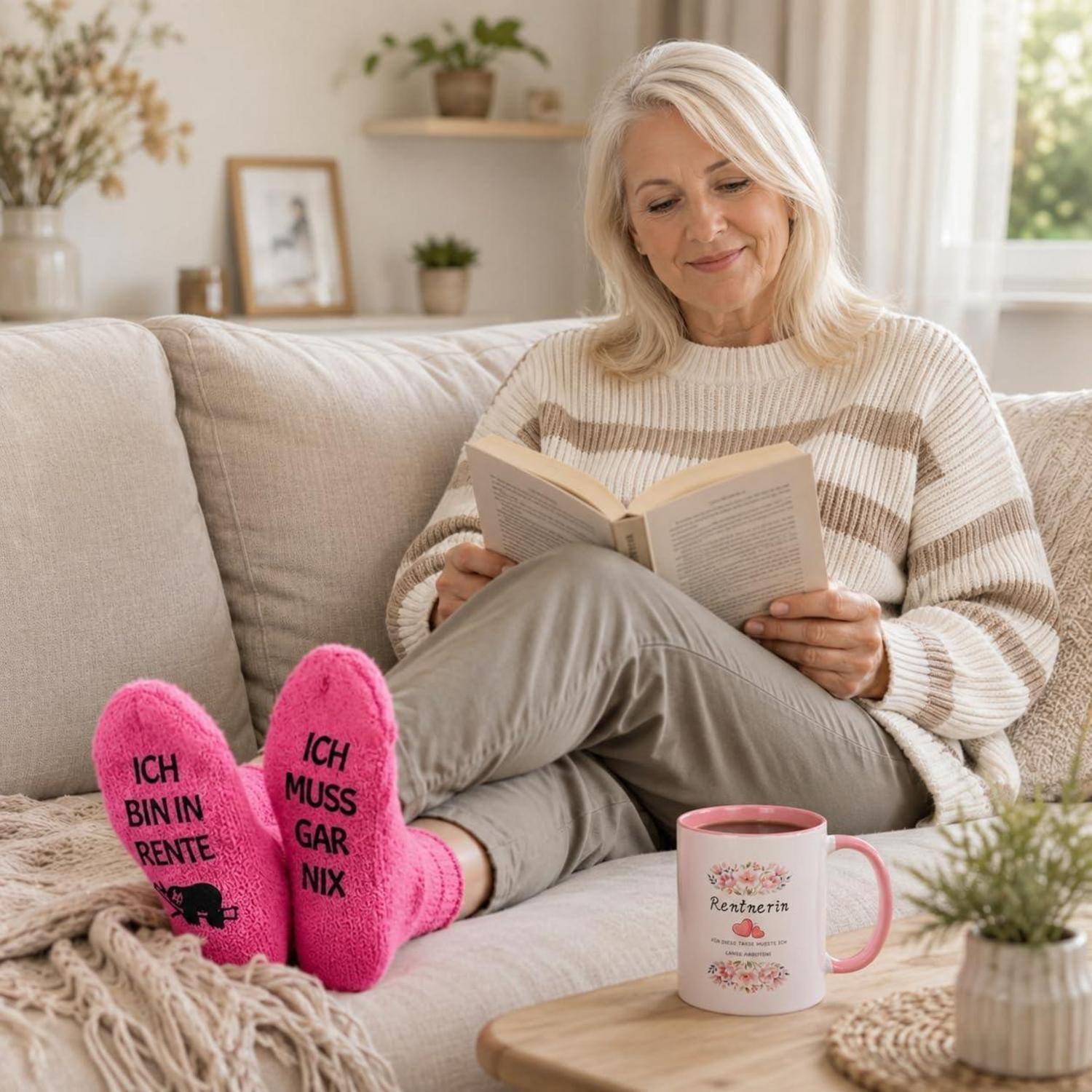 Ältere Frau, die auf einem Sofa entspannt und ein Buch liest, mit rosa Socken mit der Aufschrift 