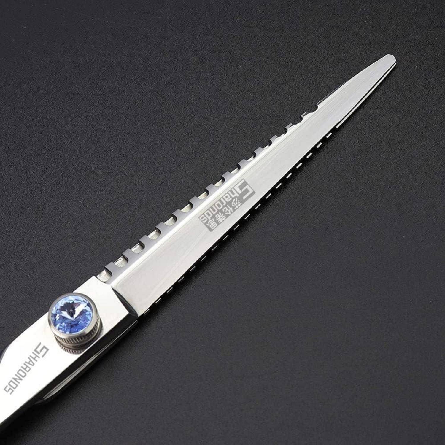Silbernes Klappmesser mit einer blauen, mit Edelsteinen besetzten Daumenschraube, gezeigt auf dunklem Hintergrund.