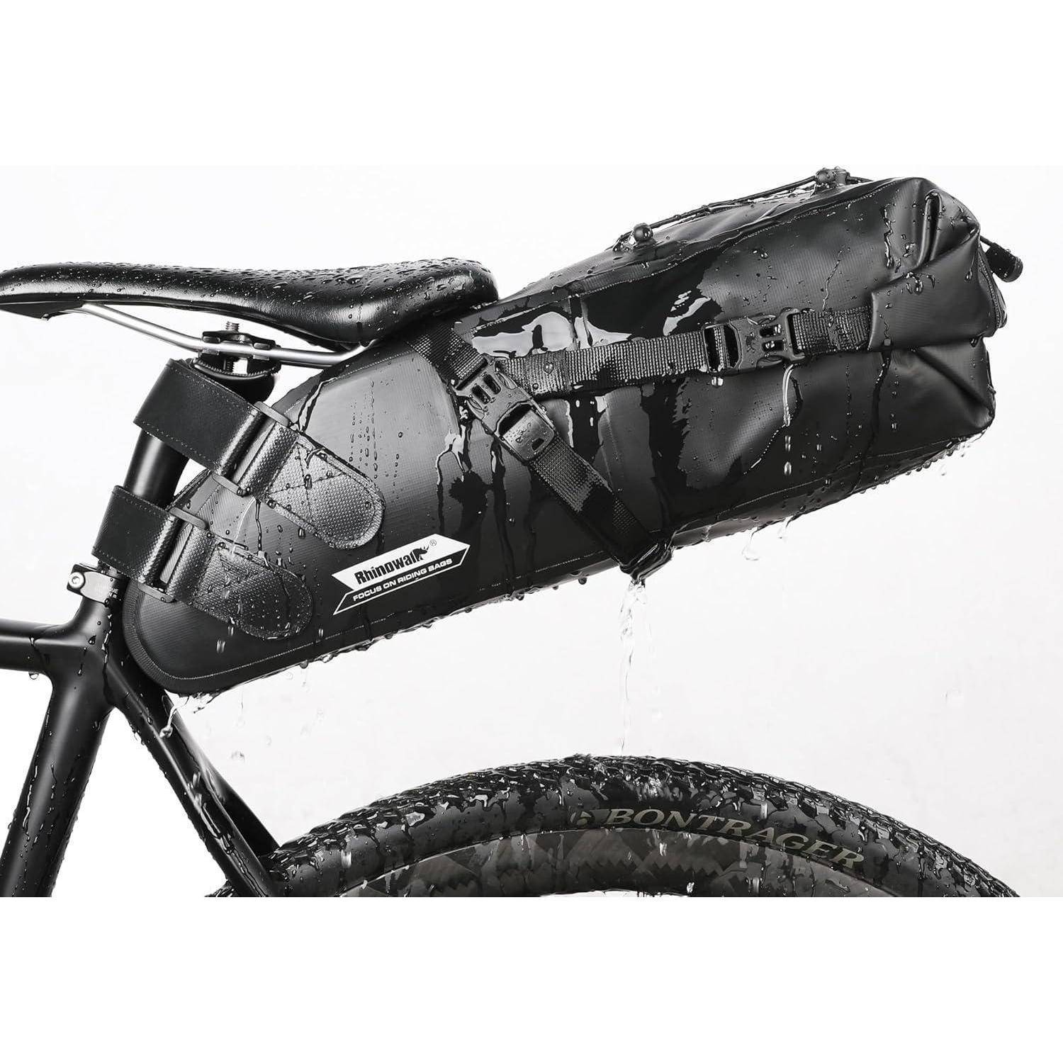 Wasserdichte Fahrradrahmentasche an einem Fahrrad befestigt, in einer Nahaufnahme mit Regentropfen auf schwarzer Ausrüstung und Hinterrad gezeigt.