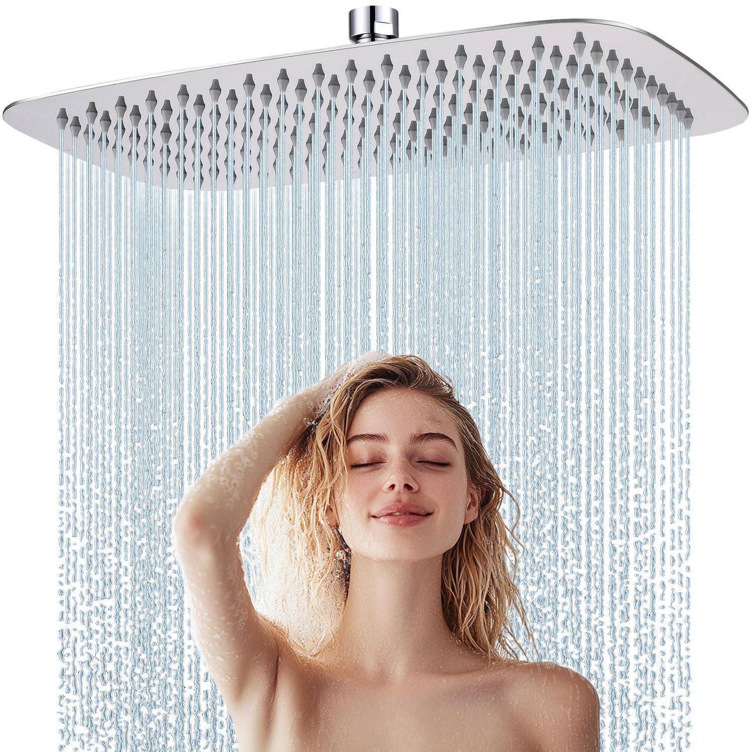 Frau, die unter einem großen Regenduschkopf duscht, die Augen geschlossen und die Hand im Haar, mit Wasser, das gegen einen weißen Hintergrund herabströmt.
