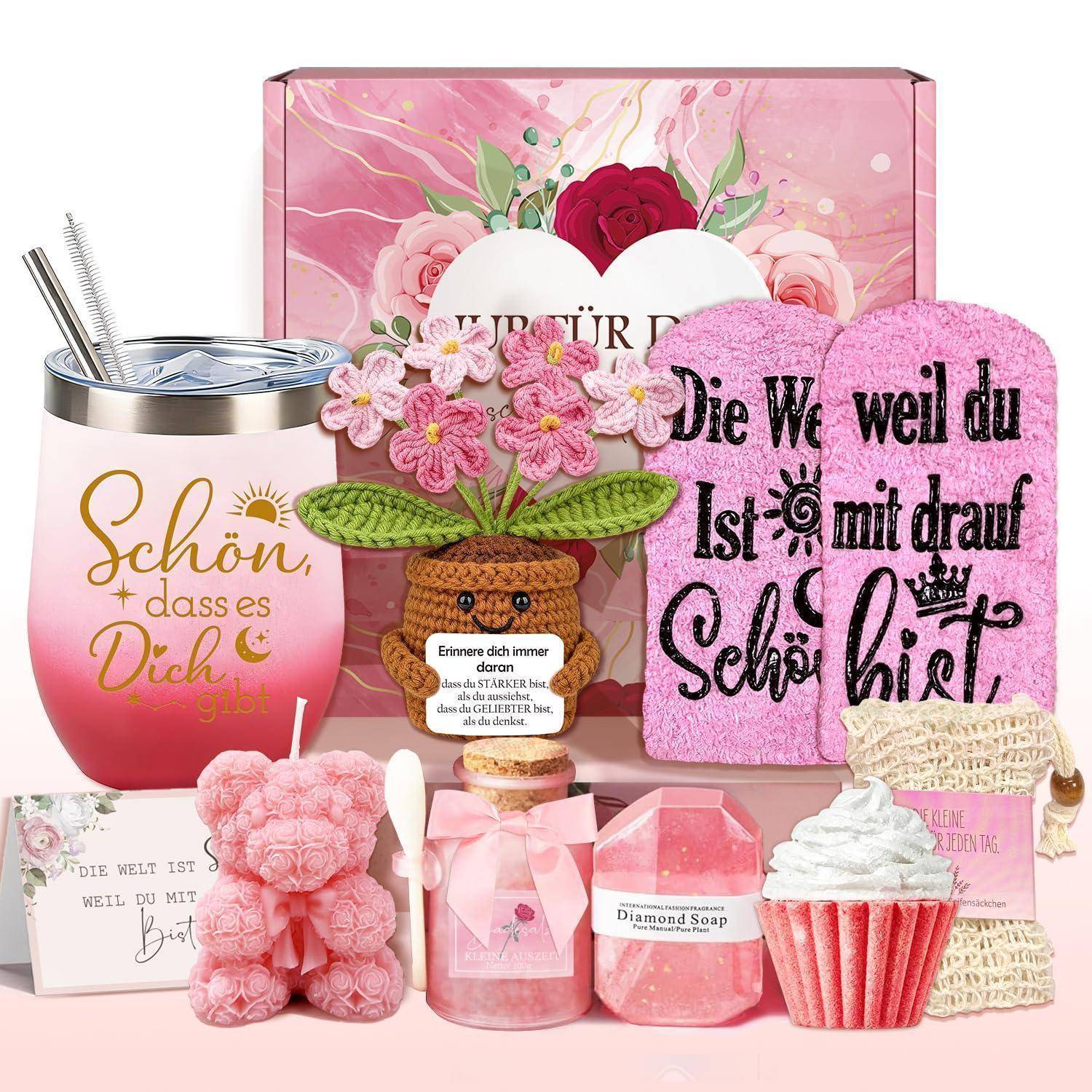 Ein Geschenkset mit rosa blumiger Verpackung, ein Becher mit Strohhalmen, ein Plüschbär, Seife, Kerzen und Handtücher mit deutschem Text, arrangiert als dekorative Geschenkpräsentation.