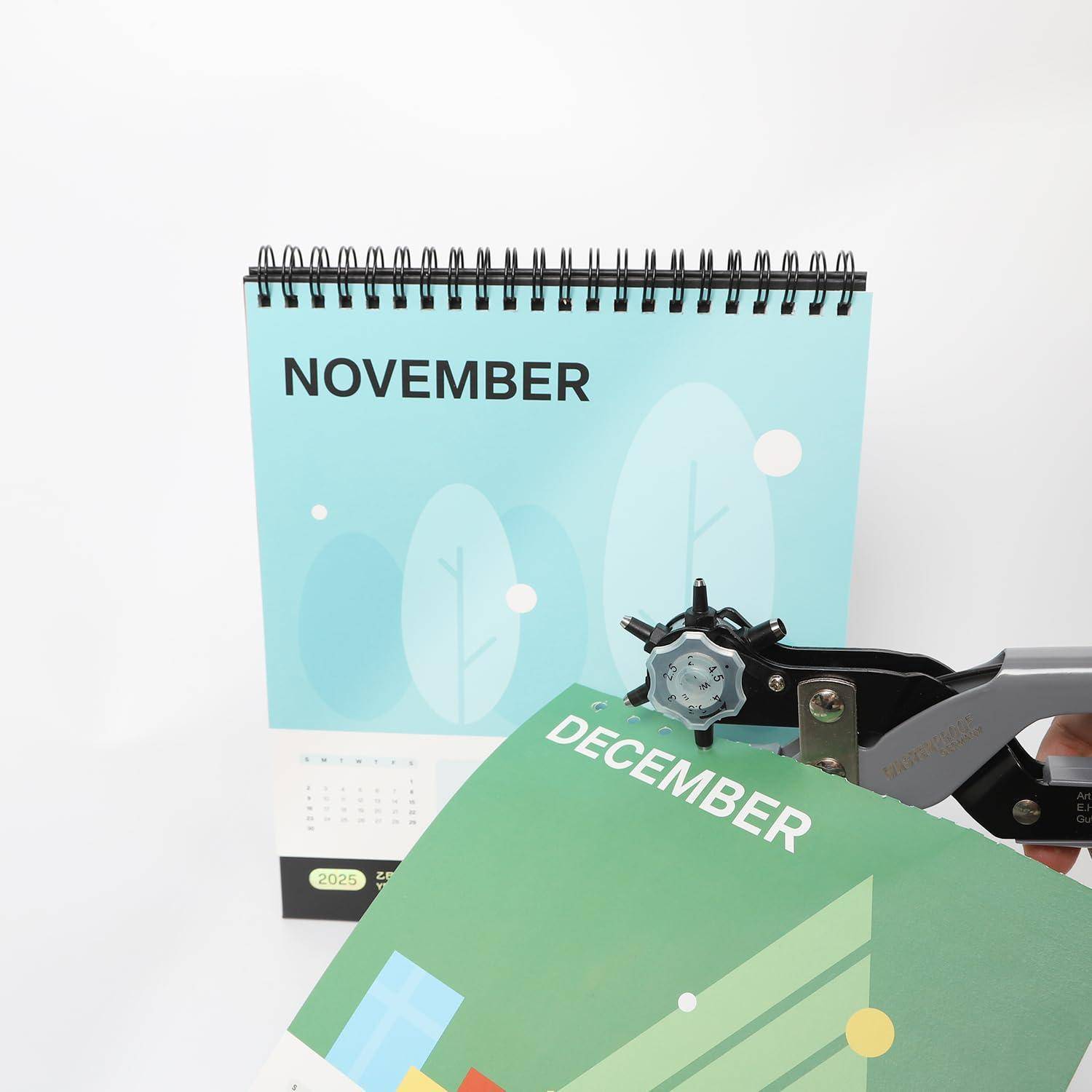 Eine Schreibtischkalenderseite mit der Beschriftung „NOVEMBER" wird von einem schwarzen Bindetool gehalten, wobei eine grüne Seite „DEZEMBER"" entfernt oder eingefügt wird.