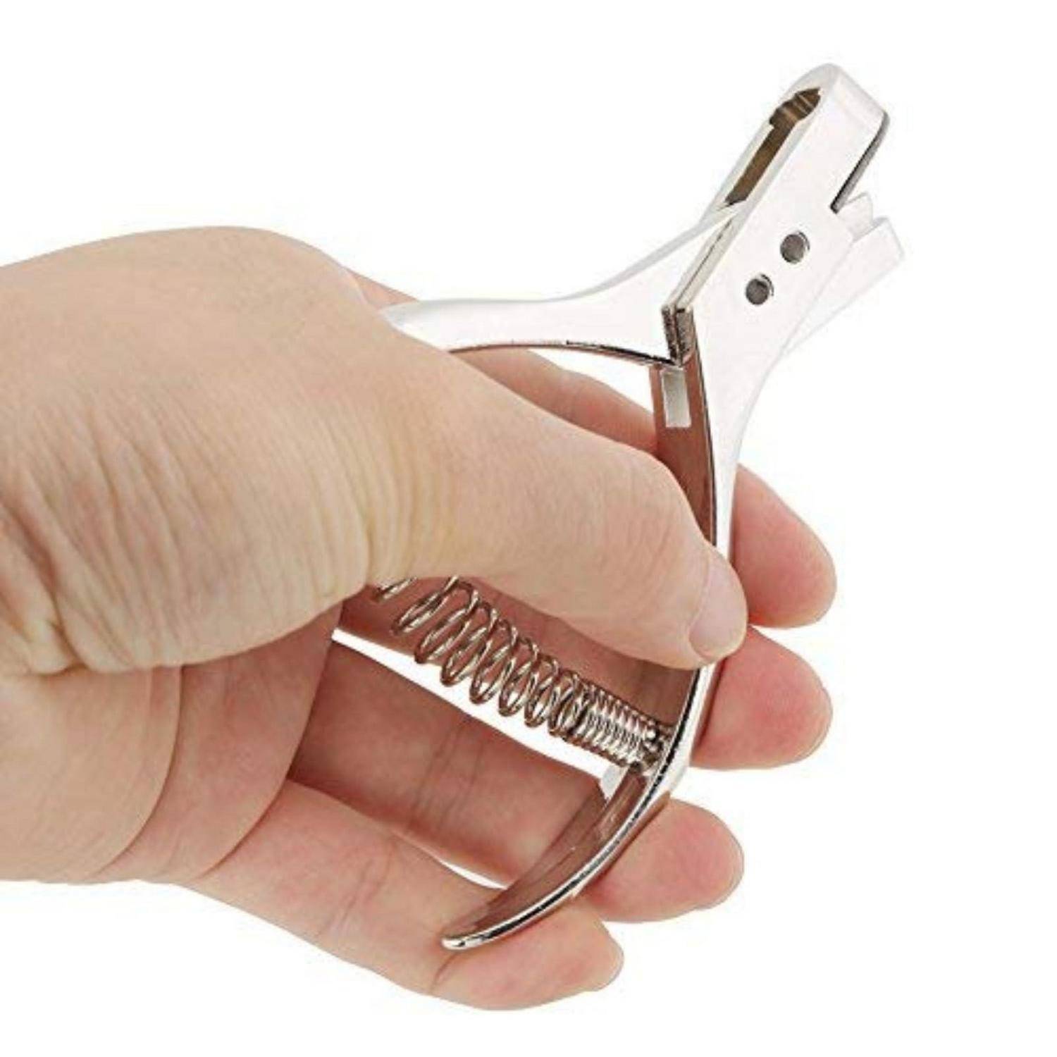 Hand, die einen metallischen, federbelasteten Nagelknipser gegen einen weißen Hintergrund hält.