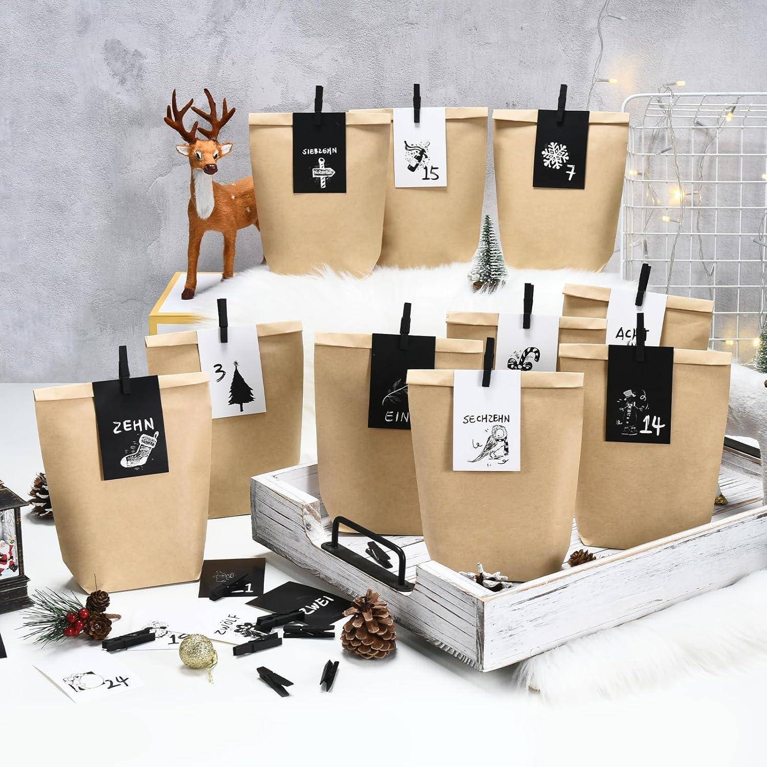 Adventskalender-Display mit braunen Papiertüten nummeriert von 1 bis 24, befestigt in einer rustikalen weißen Kiste neben einer kleinen Hirschfigur und Tannenzapfen.