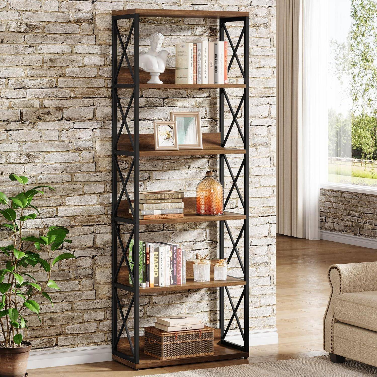 Hohes Industrie-Bücherregal mit Holzregalen und schwarzem Metallrahmen, das Bücher, Rahmenfotos, eine Büste und Dekoration vor einer Backsteinwand in einem hellen Wohnzimmer hält.