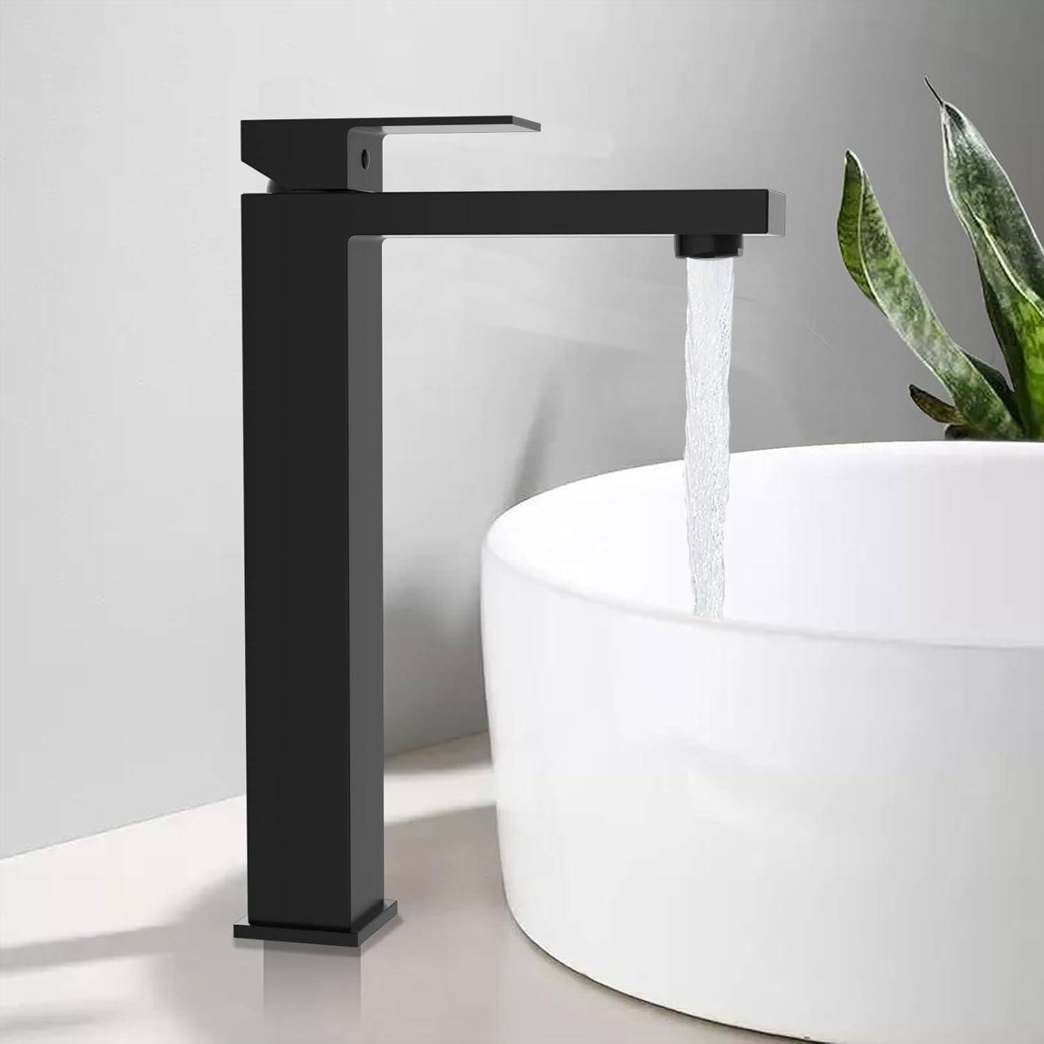 Moderner schwarzer Wasserhahn im Badezimmer, der in ein weißes rundes Aufsatzwaschbecken neben einer grünen Pflanze läuft.