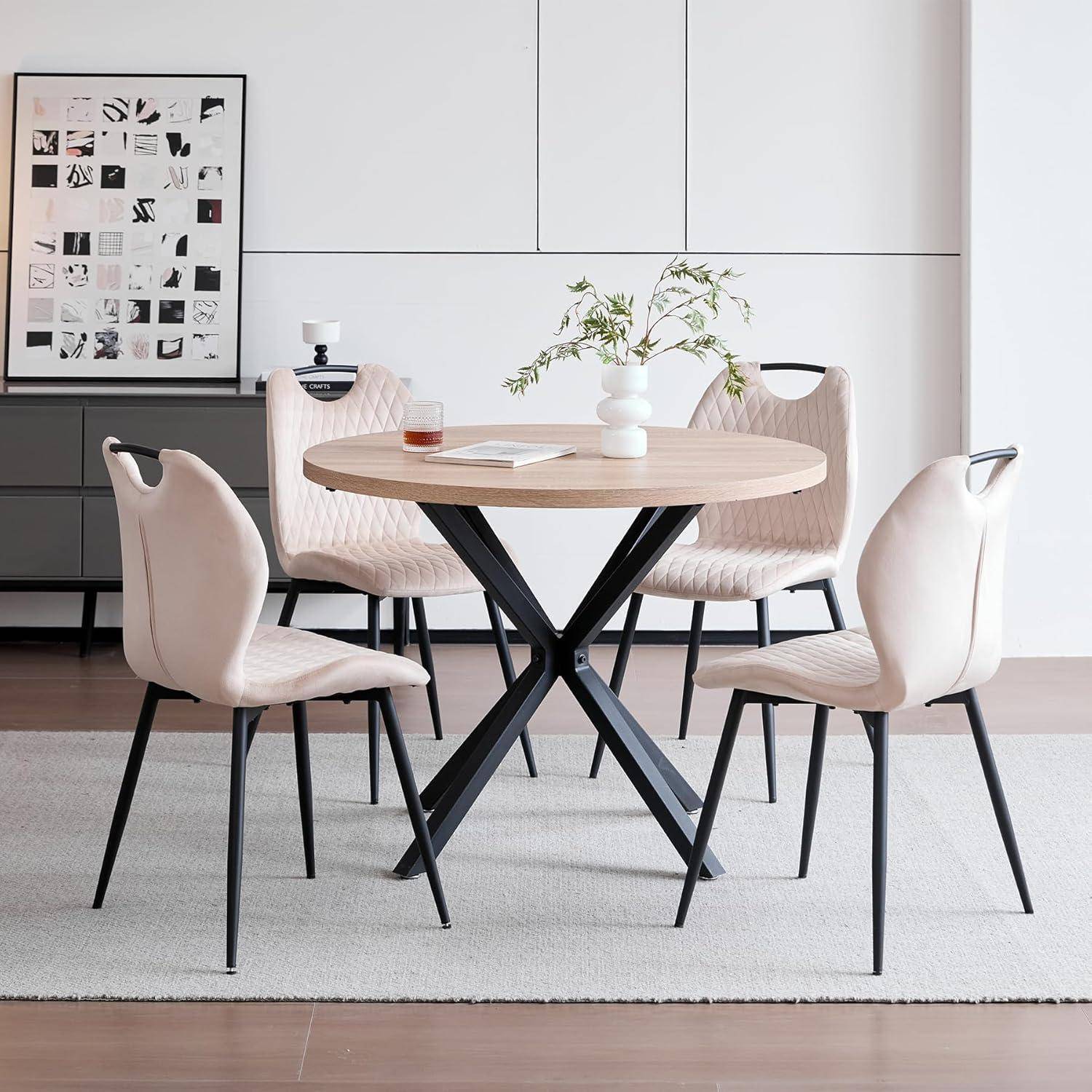 Modernes Esszimmer mit rundem Holztisch, vier gepolsterten Stühlen, Vasenmittelstück und gerahmter Wandkunst