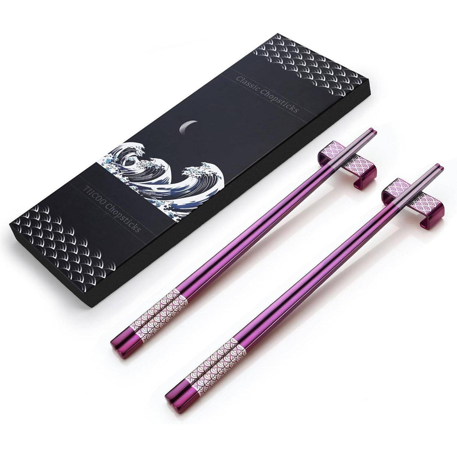 Paar violetter Titanium-Stäbchen mit strukturierten quadratischen Ablagen neben einer schwarzen Präsentationsschachtel mit der Aufschrift „Titanium Chopsticks