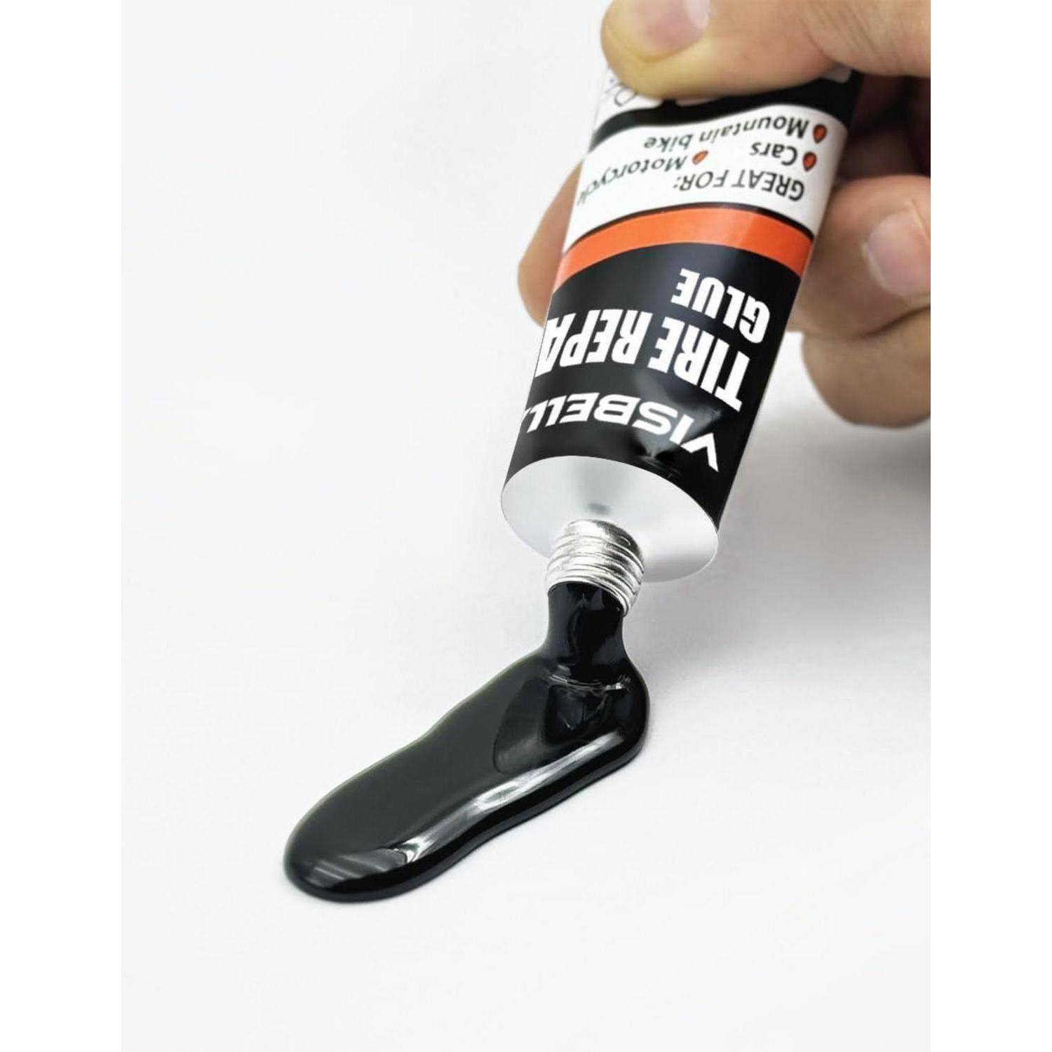 Eine Hand drückt schwarze Farbe aus einer Tube mit der Aufschrift „VISBEL TIG REFLECT GLUE" auf eine weiße Oberfläche.