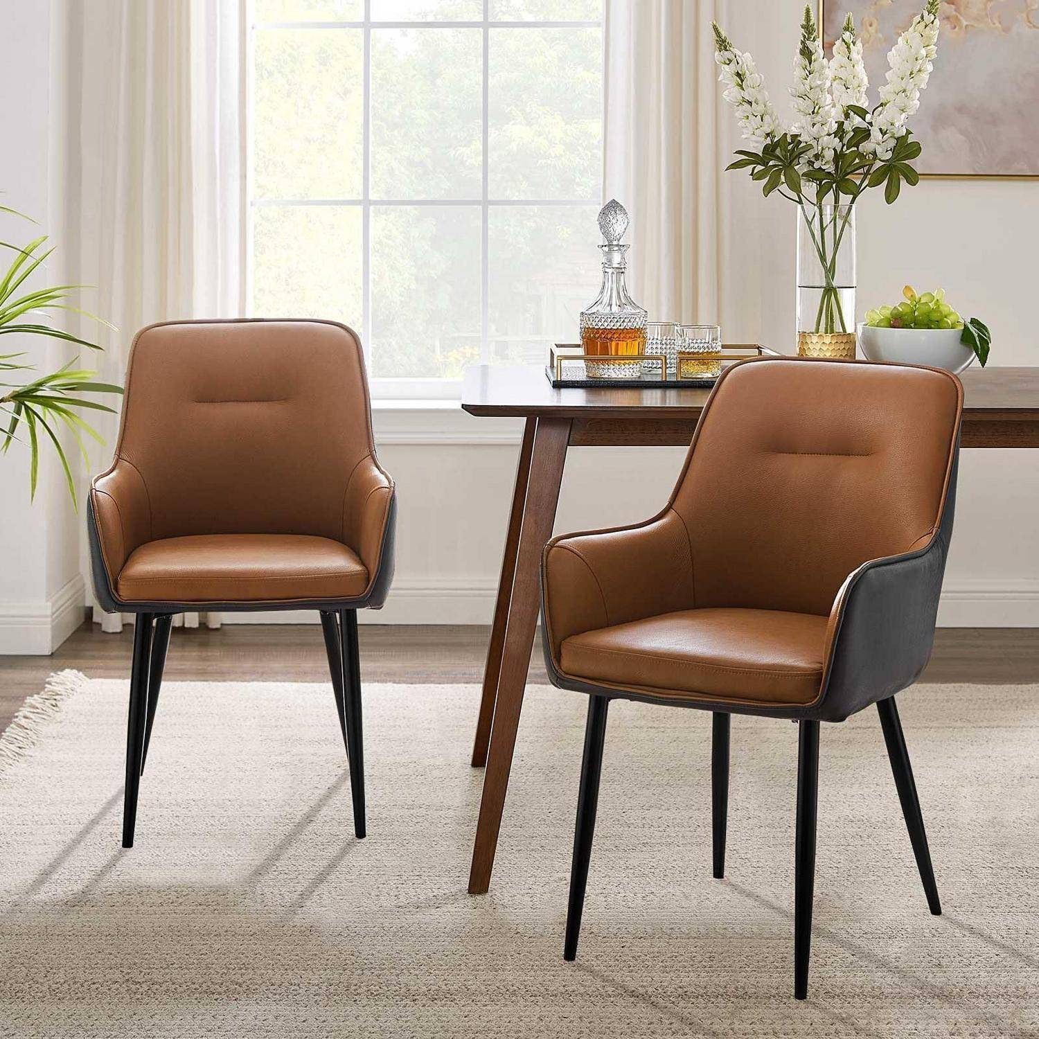 Zwei braune Lederstühle in einem hellen Zimmer neben einem Holztisch mit einer Karaffe und Blumen.