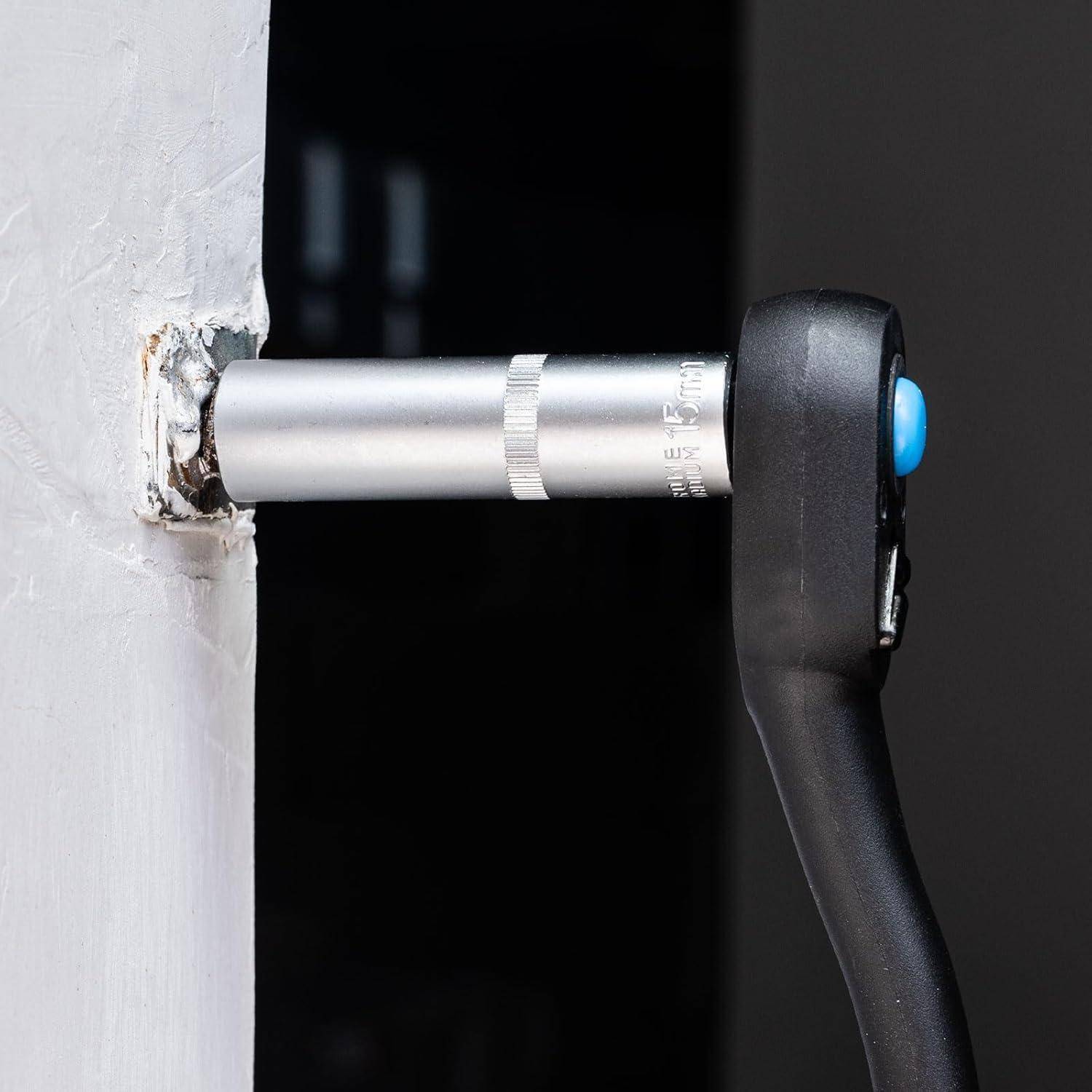 Nahaufnahme eines Steckschlüssels mit schwarzem Griff mit blauem Knopf, der an einer silbernen Verlängerung befestigt ist und in eine an der Wand montierte Befestigung oder Rohroffnung eingeführt wird.
