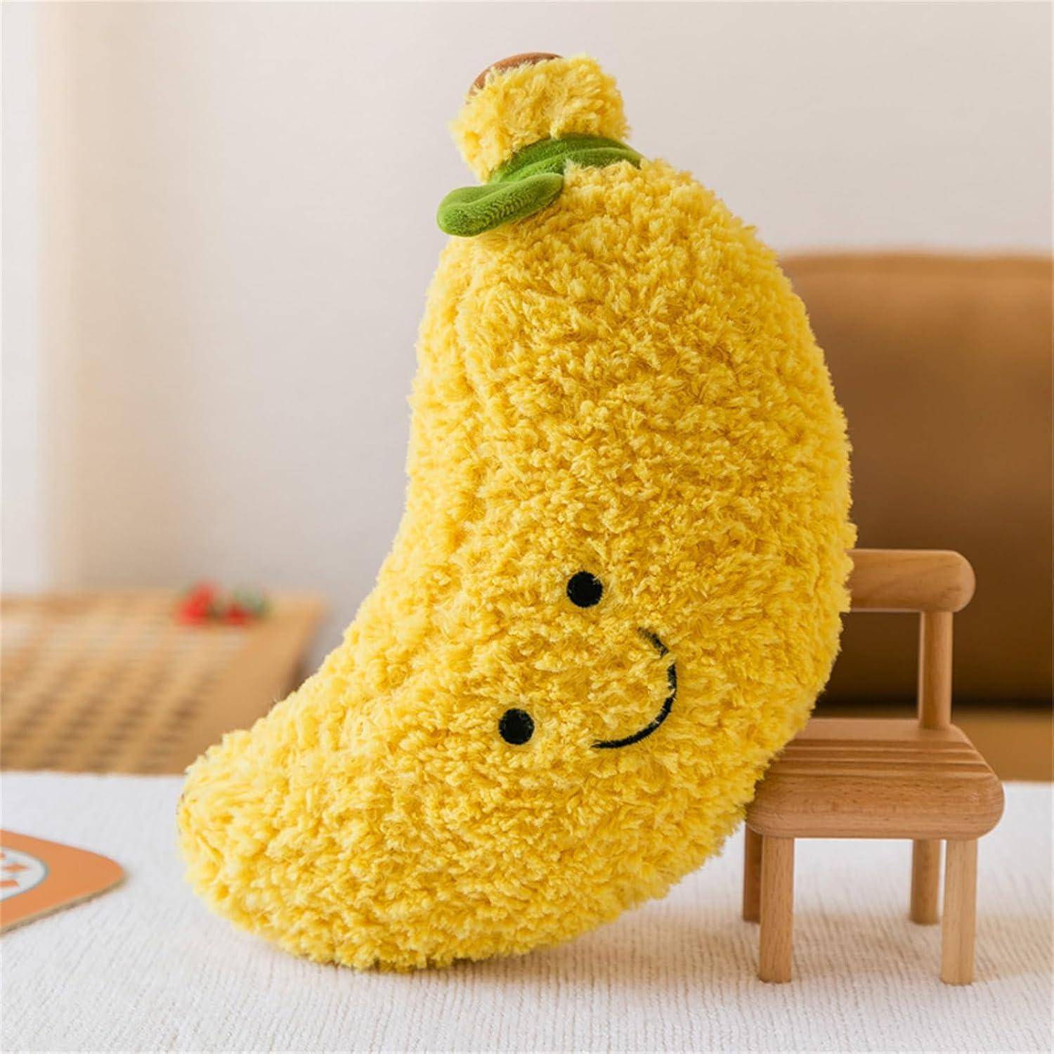 Ein weiches gelbes Plüschtier in Bananenform mit einem lächelnden Gesicht lehnt sich an einen kleinen Holzstuhl auf einem Bett.