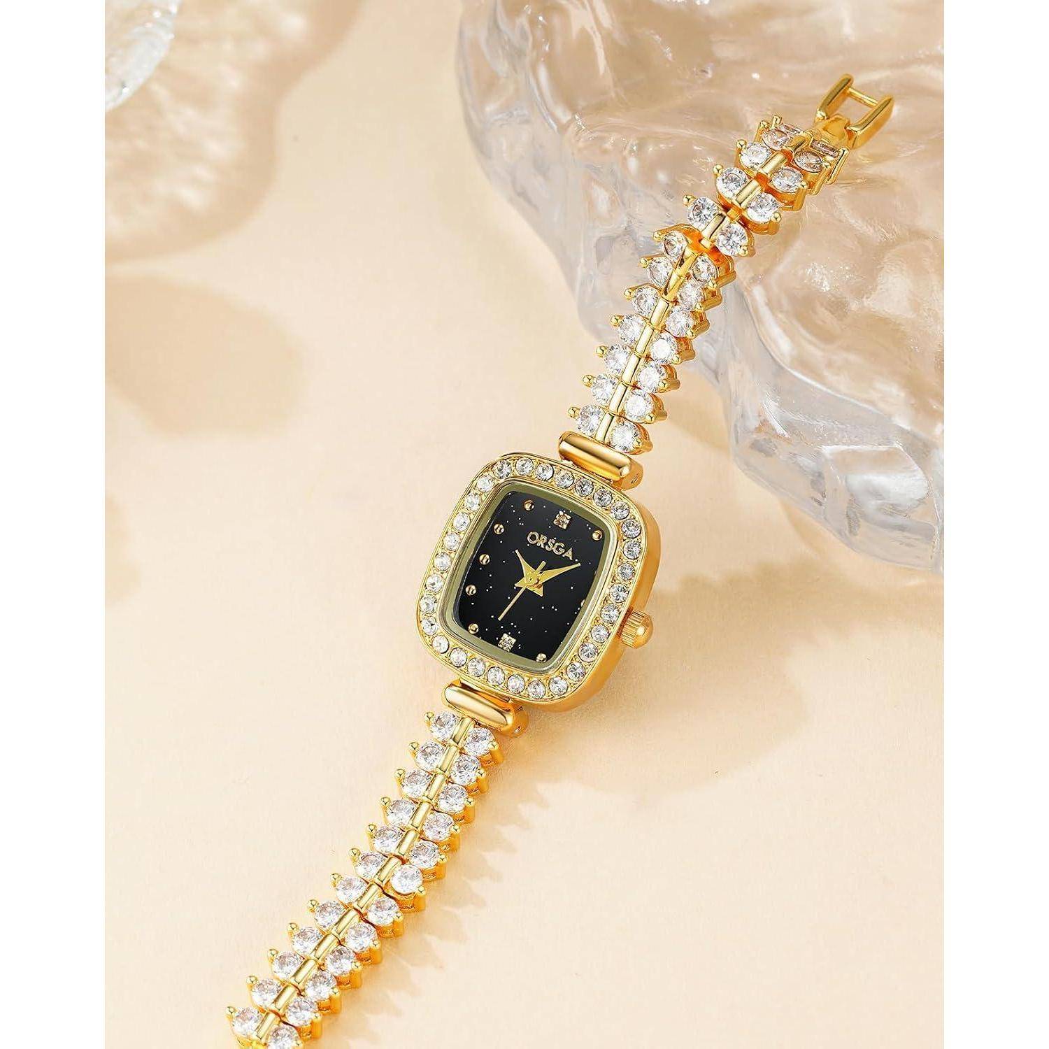 Goldarmbandur mit schwarzem quadratischem Zifferblatt und kristallbesetztem Armband auf hellem Hintergrund.