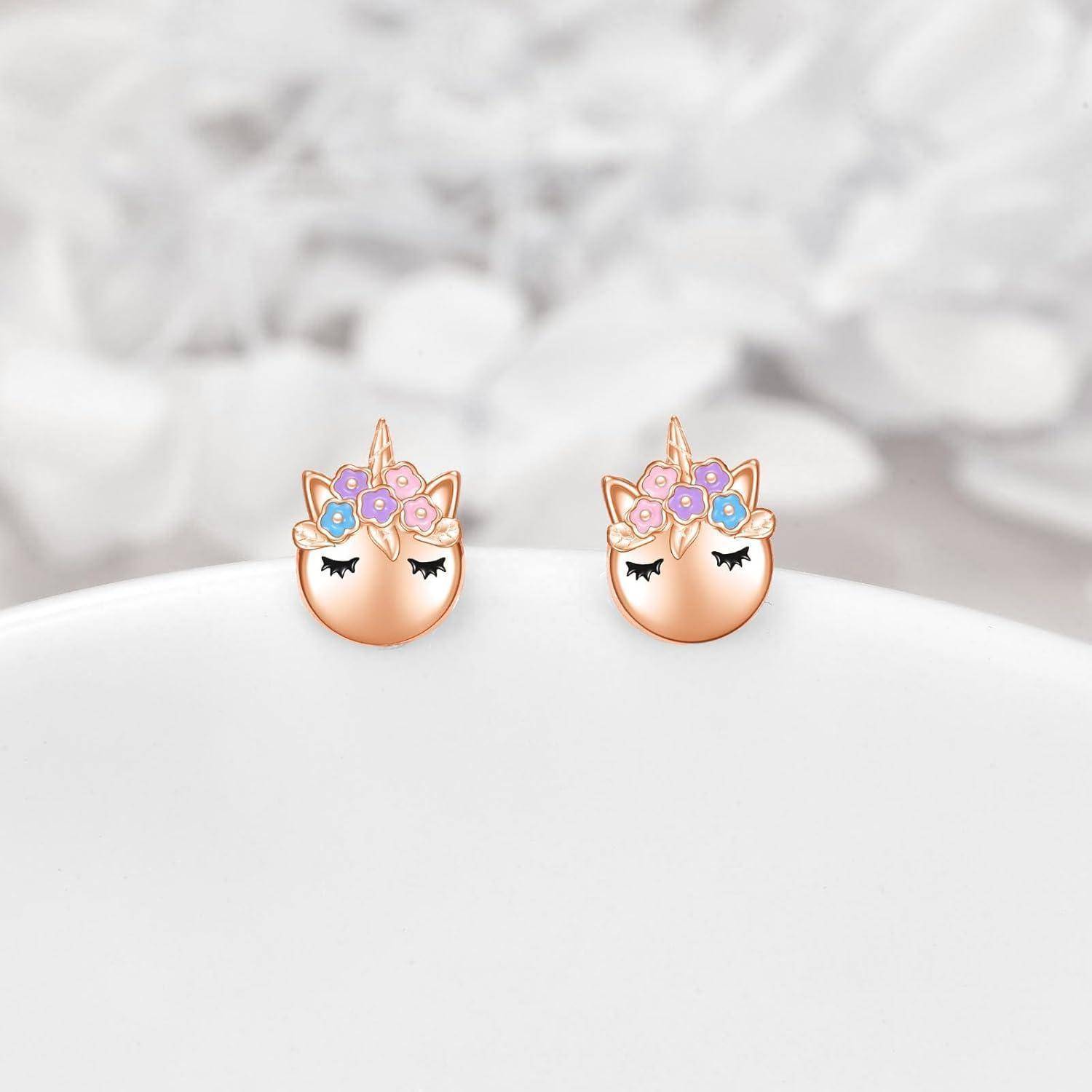 Paar einhornthematischer Stecker-Ohrringe mit geschlossenen Augen und pastellfarbenen Blütenkronen auf einer weißen Oberfläche.