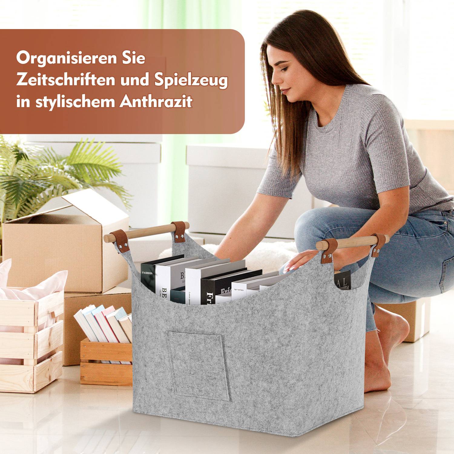 Frau kniet hin und ordnet Bücher und Spielzeug in einem grauen Stofflagerbehälter in einem hellen Raum; der Text lautet „Organisieren Sie Zeitschriften und Spielzeug in stylischem Anthrazit".