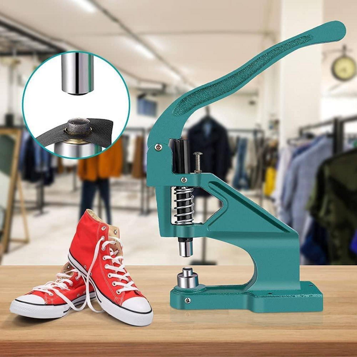 Grüne tragbare Metallpresse zum Befestigen von Schuhösen, dargestellt neben roten Sneakern in einer Kleidungswerkstatt, mit einer Nahaufnahme des Pressenkopfes im Einsatz.