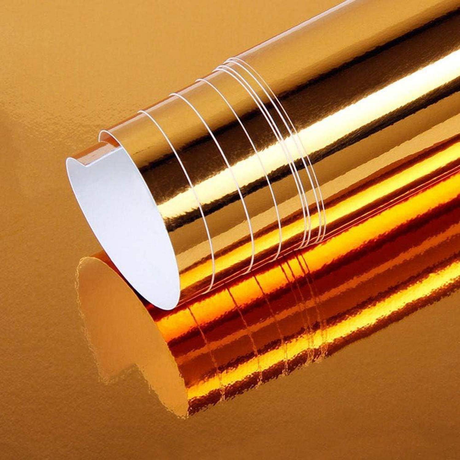 Nahaufnahme von glänzenden Gold- und Orange-Reflektionsfolienrollen, die sich auf einem metallischen goldfarbenem Hintergrund überlappen.